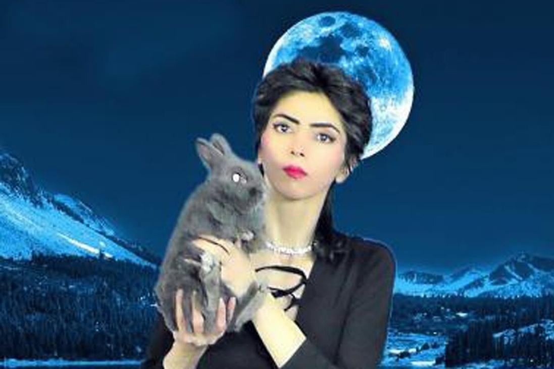An image of YouTube shooter Nasim Aghdam holding a rabbit in front of a moon and mountains.