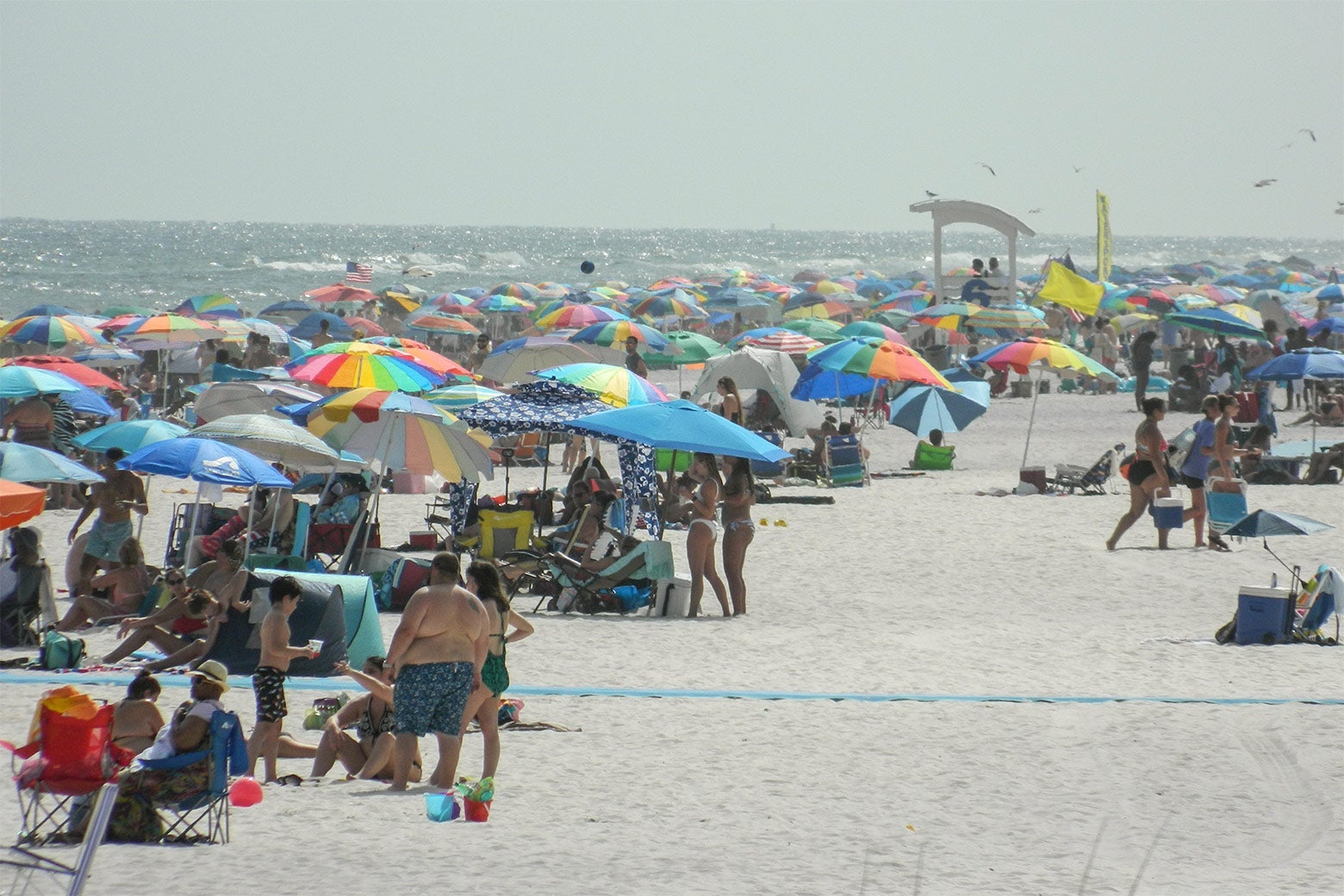 Many people crowded on a beach on a foggy day.