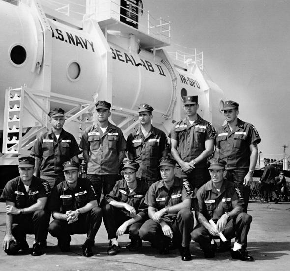 Sealab II's first crew poses in front of the U.S. Navy's new habitat before it's lowered to the seabed. 