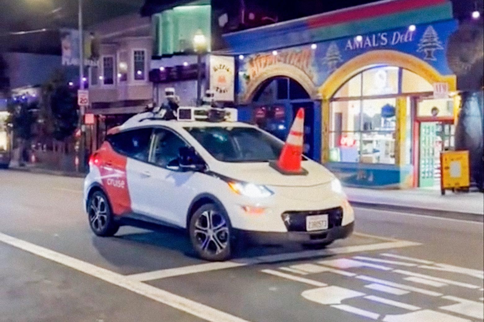 A Cruise robotaxi disabled by a cone on its hood.