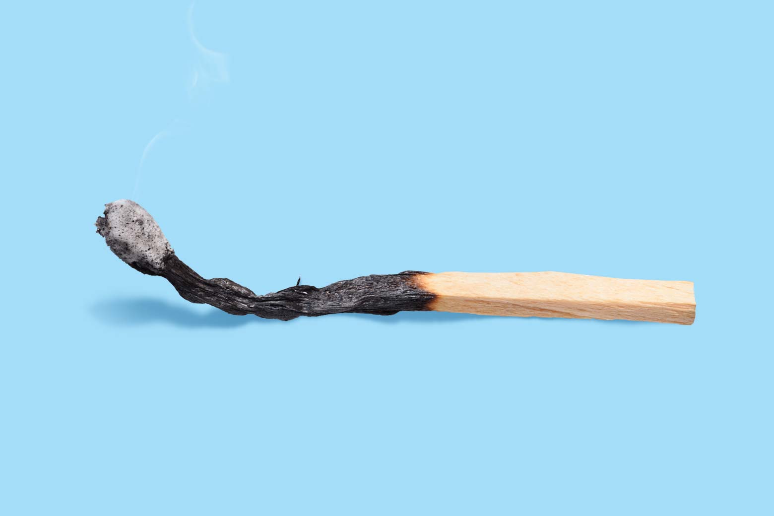 Photo illustration of a burnt match against a blue background.