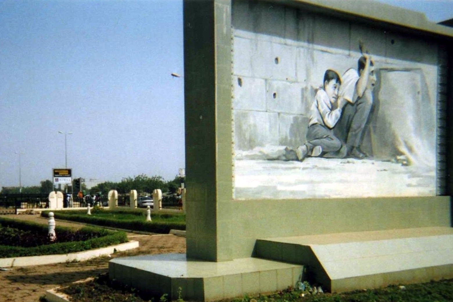 Mural que representa a un niño pequeño protegido por su padre mientras las balas caen sobre ellos.