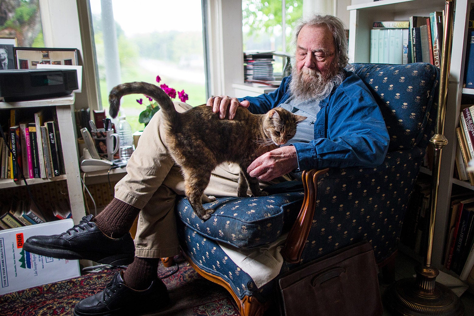 Donald Hall in a chair with a cat on his lap.
