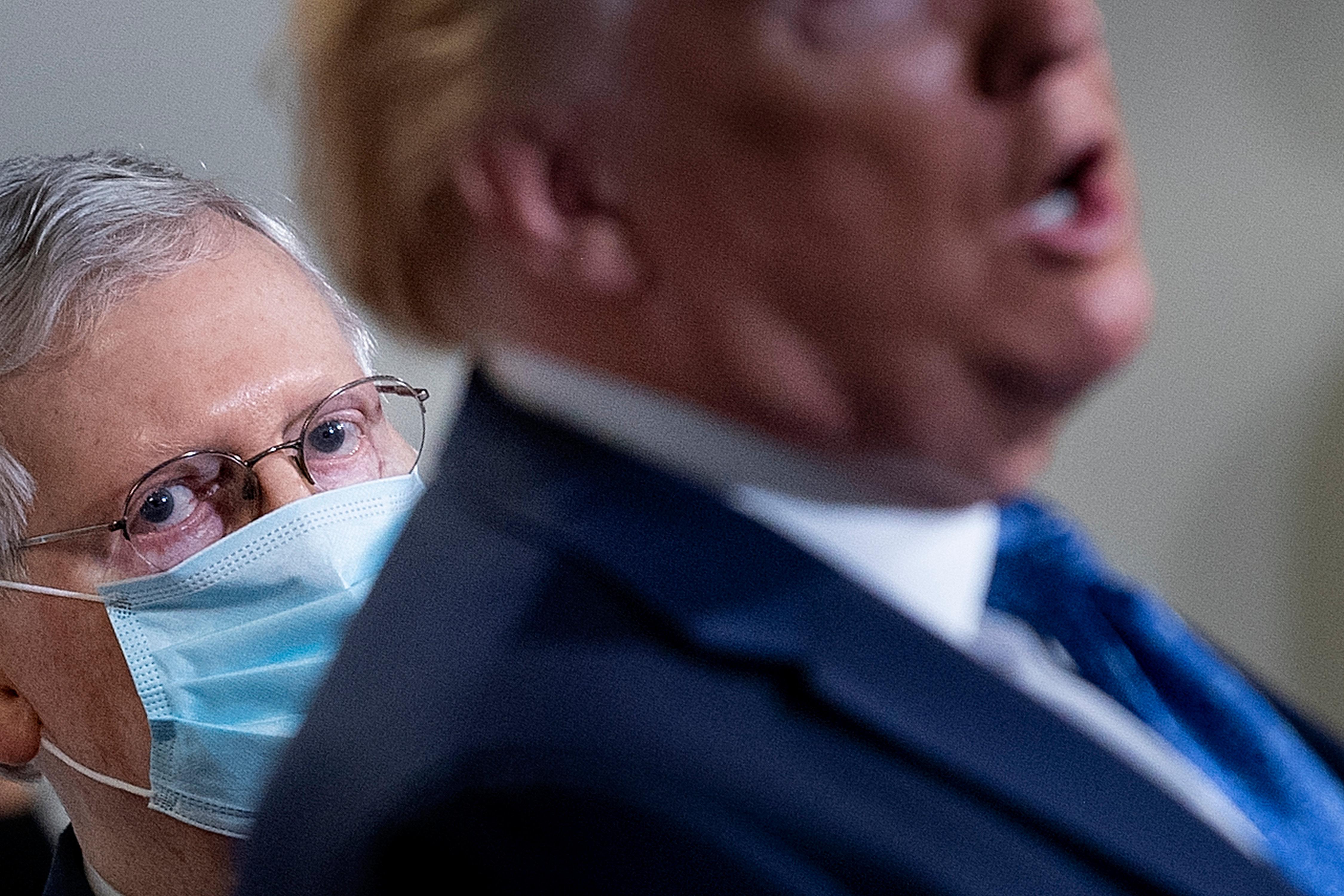 McConnell, wearing a mask, listens as Trump speaks