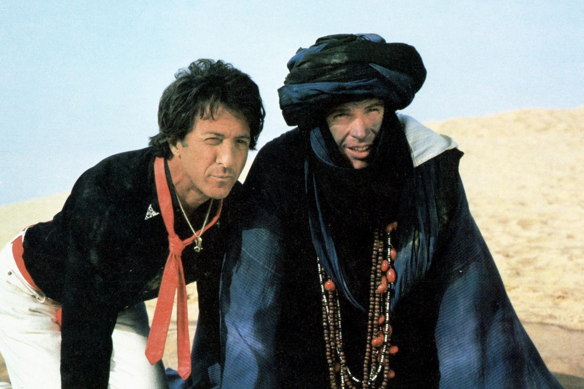 Dustin Hoffman and Warren Beatty kneeling on sand in the desert.