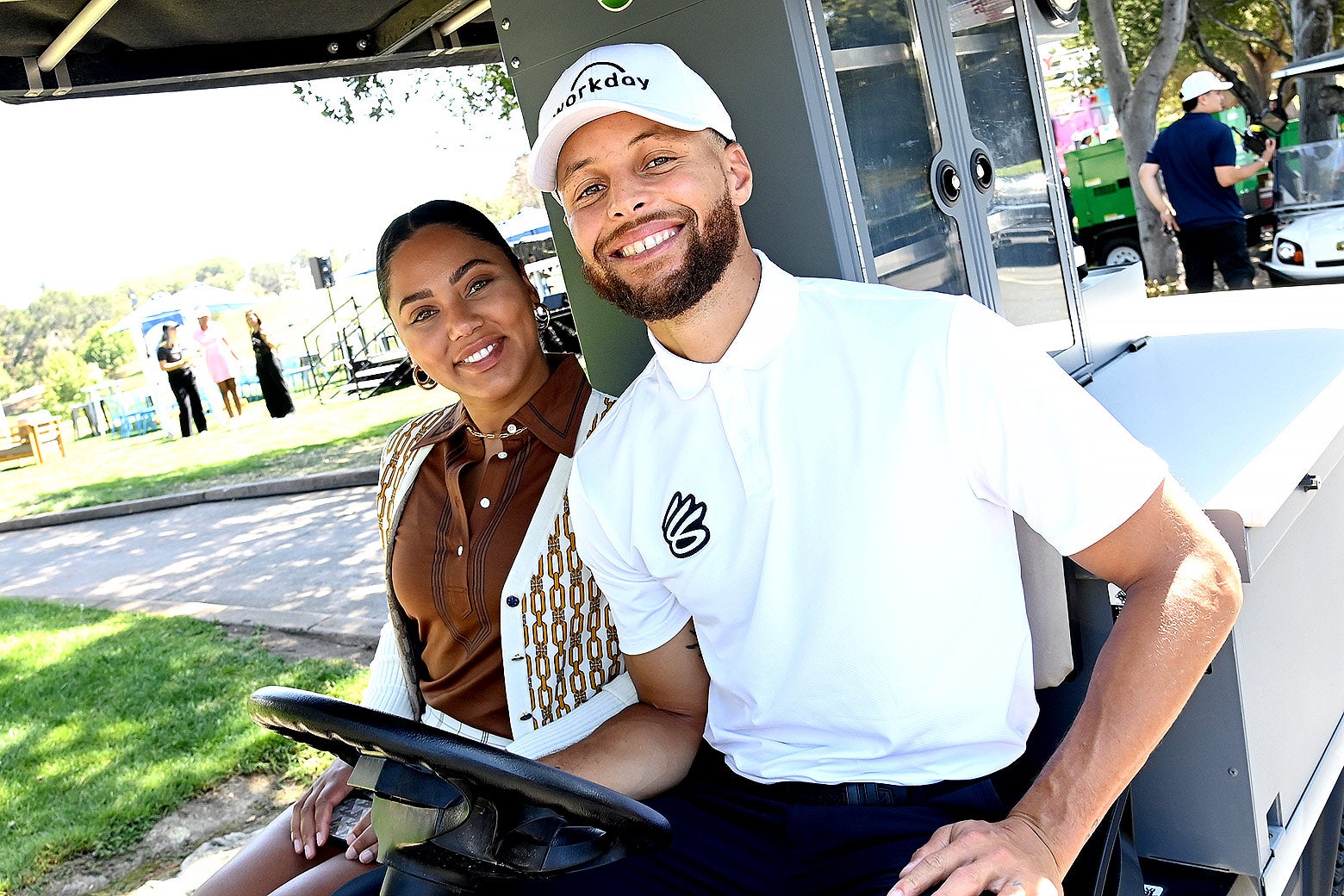 Steph and Ayesha Curry smiling in a golf cart.