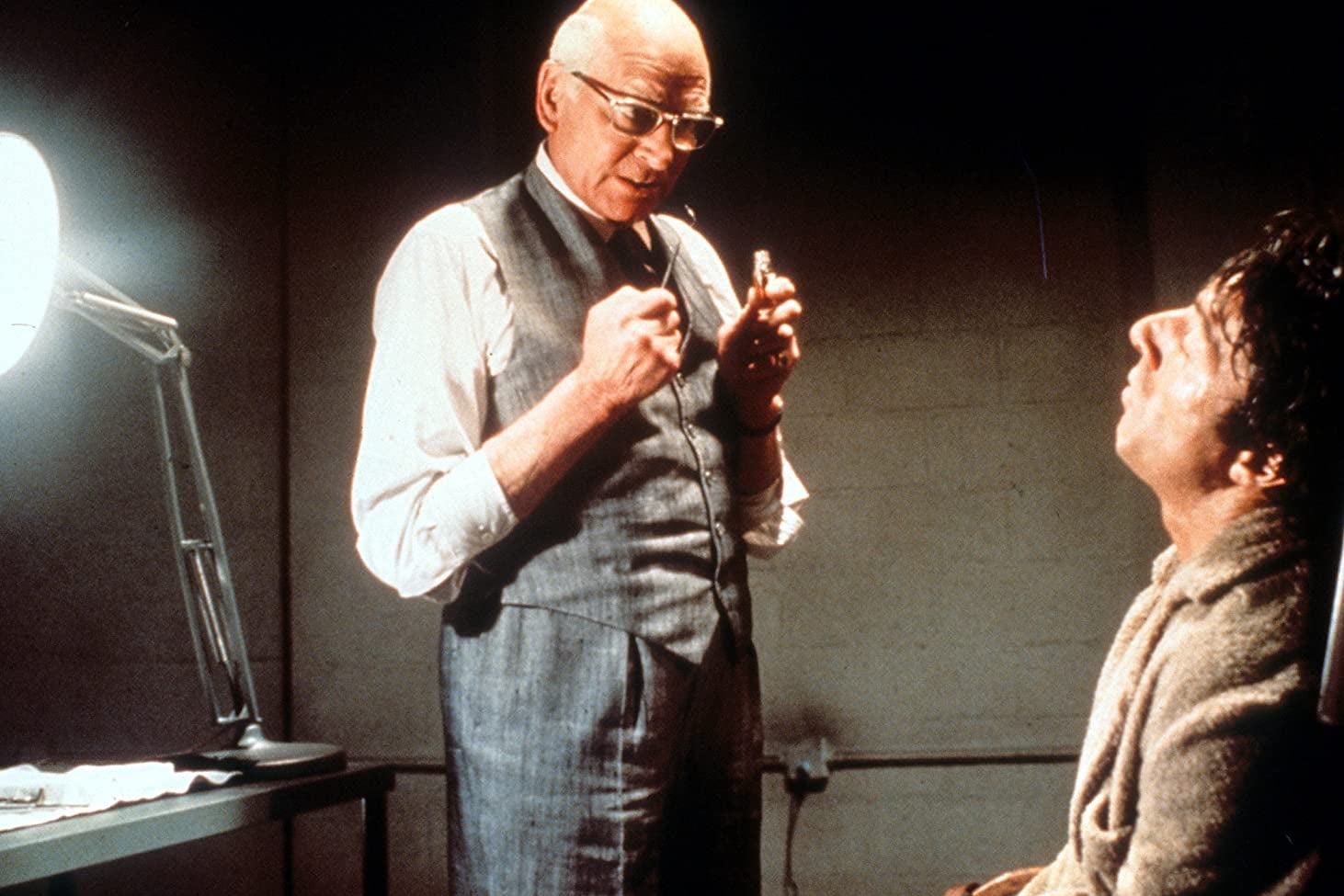 Laurence Olivier stands over Dustin Hoffman holding dental tools.
