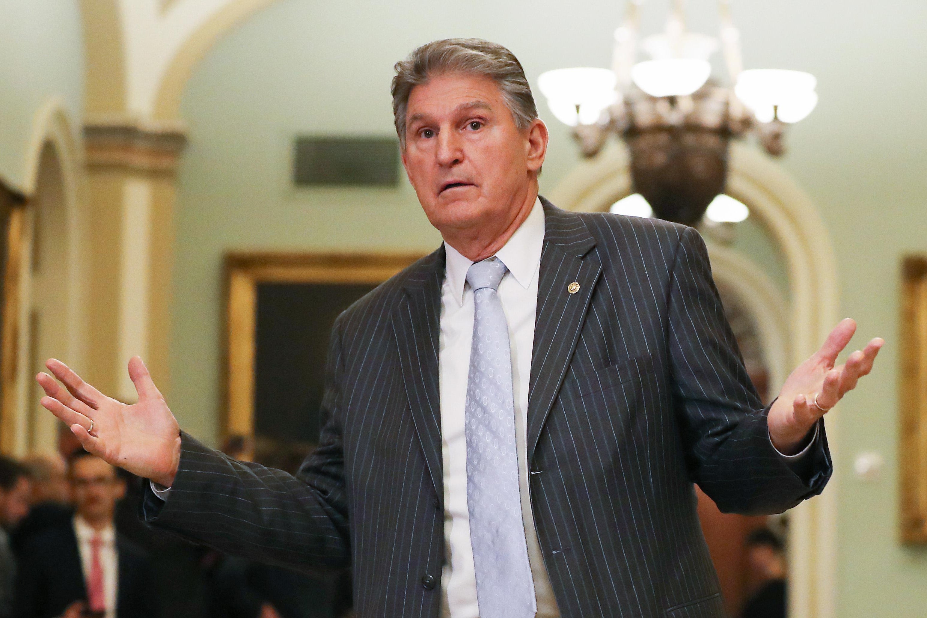 Joe Manchin raises his arms outside the senate chamber
