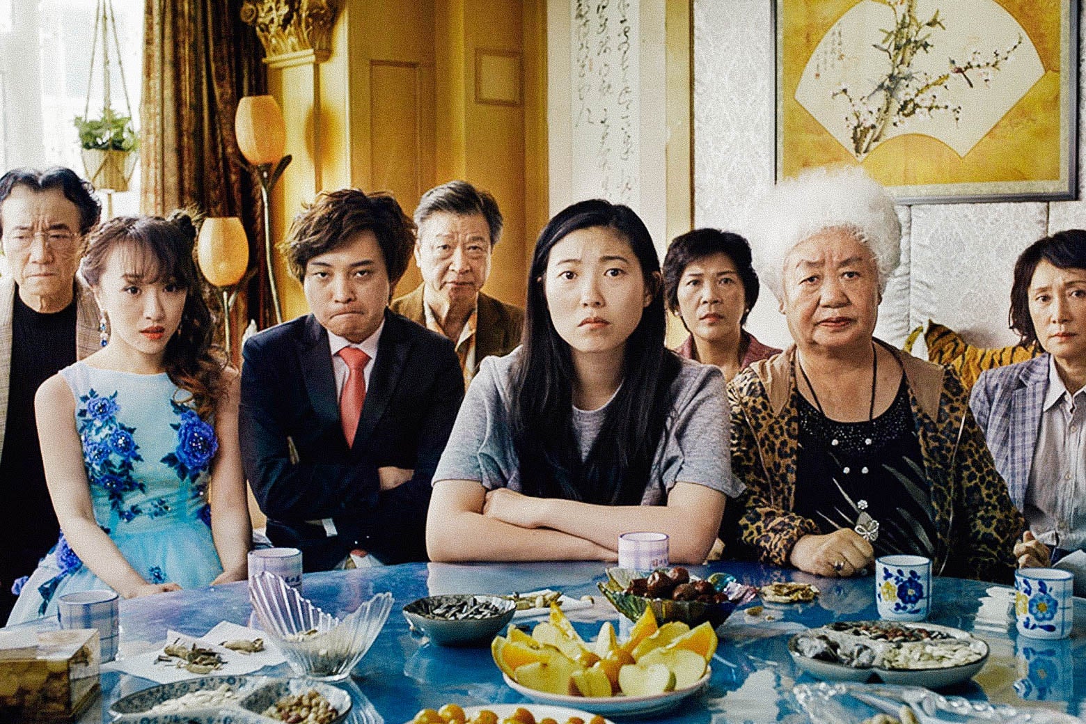 The cast of The Farewell sits at a table in a still from the movie.