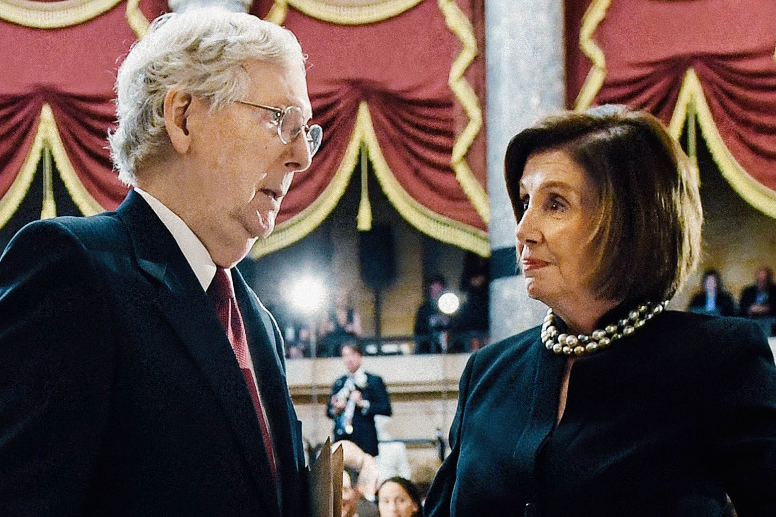 Mitch McConnell and Nancy Pelosi look at each other.