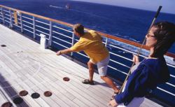 Couple playing shuffleboard on cruise ship deck.