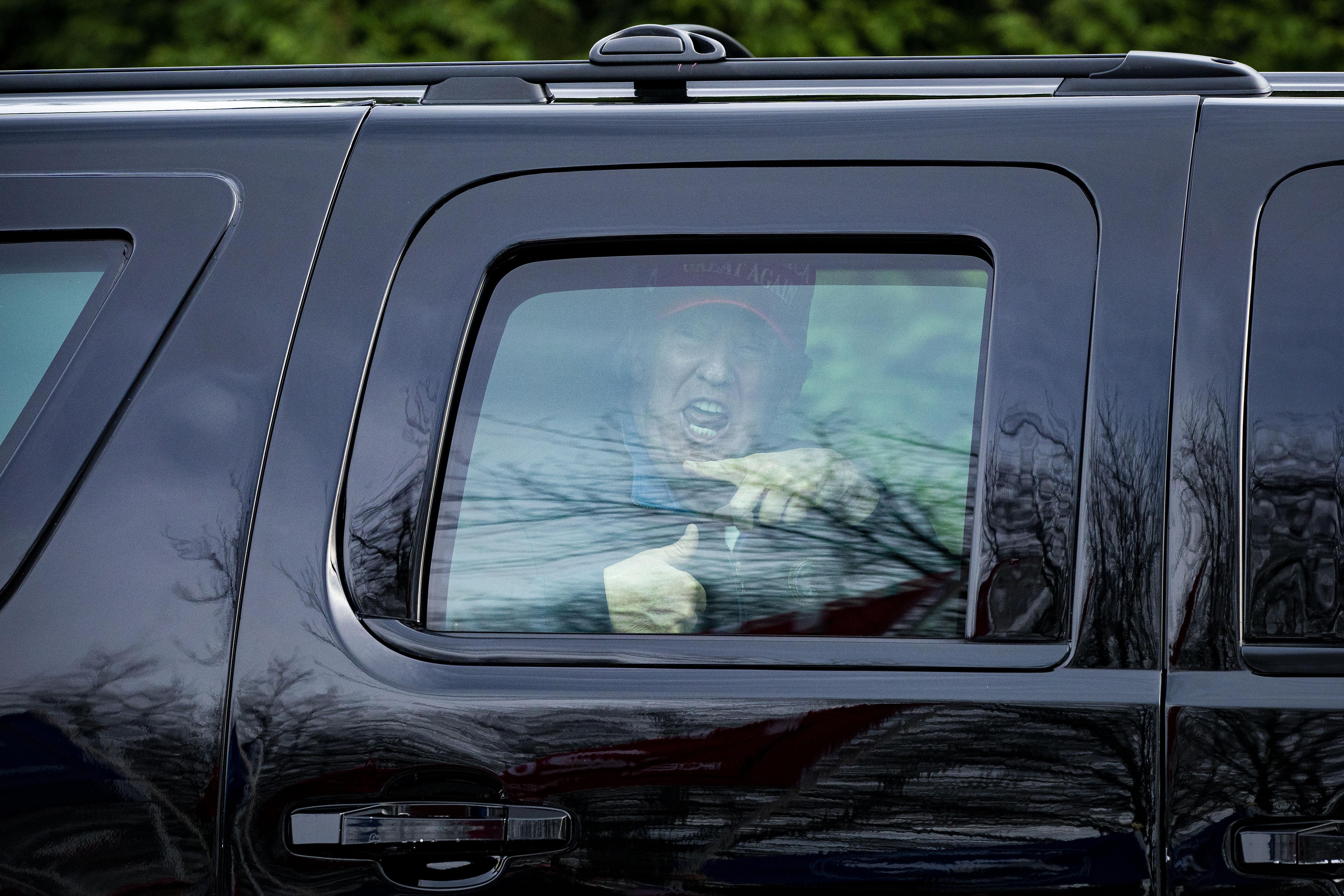 Donald Trump giving an enthusiastic thumbs up through the window of his motorcade.