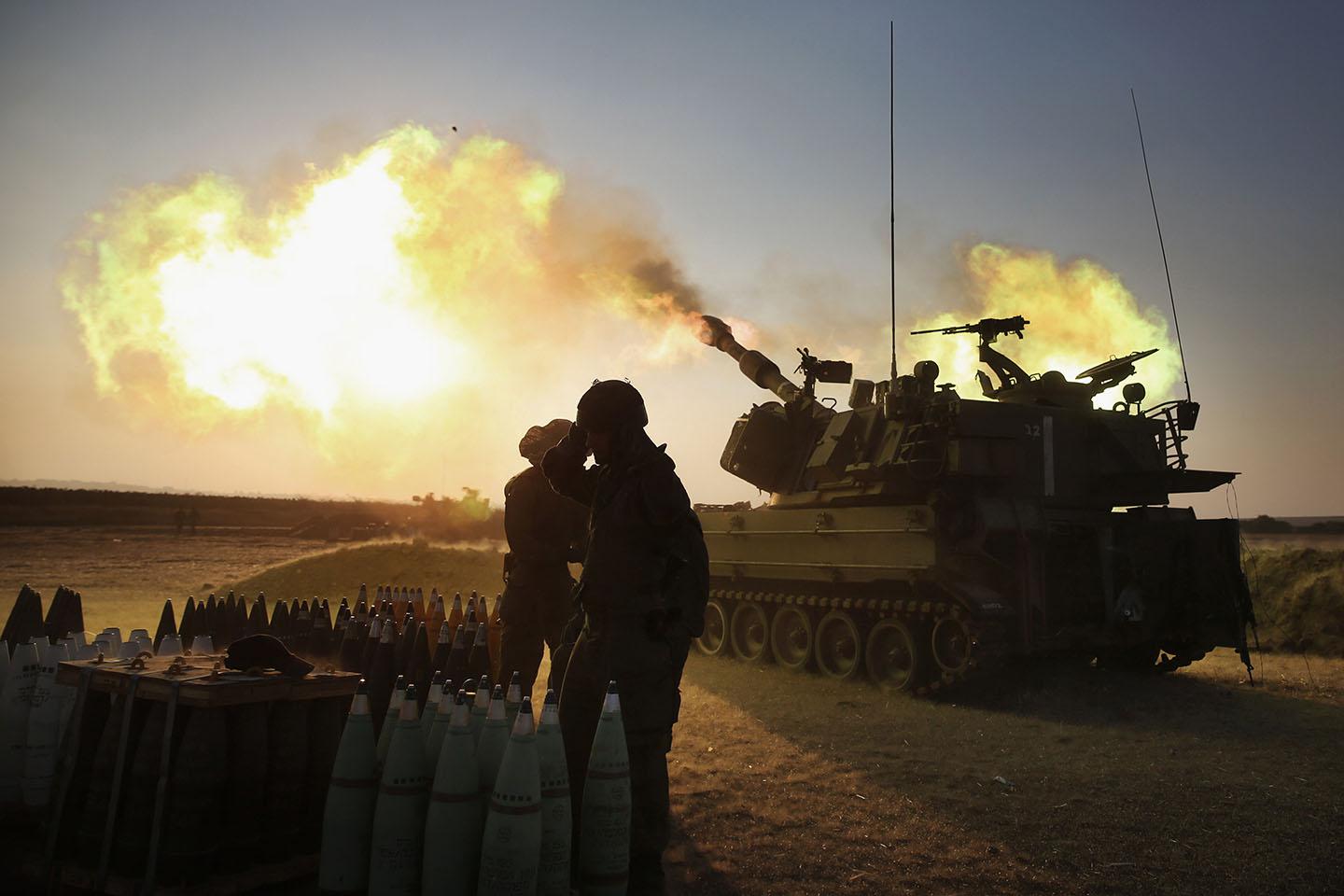 Israeli soldiers of the 155mm artillery cannons unit fire towards the Gaza Strip.