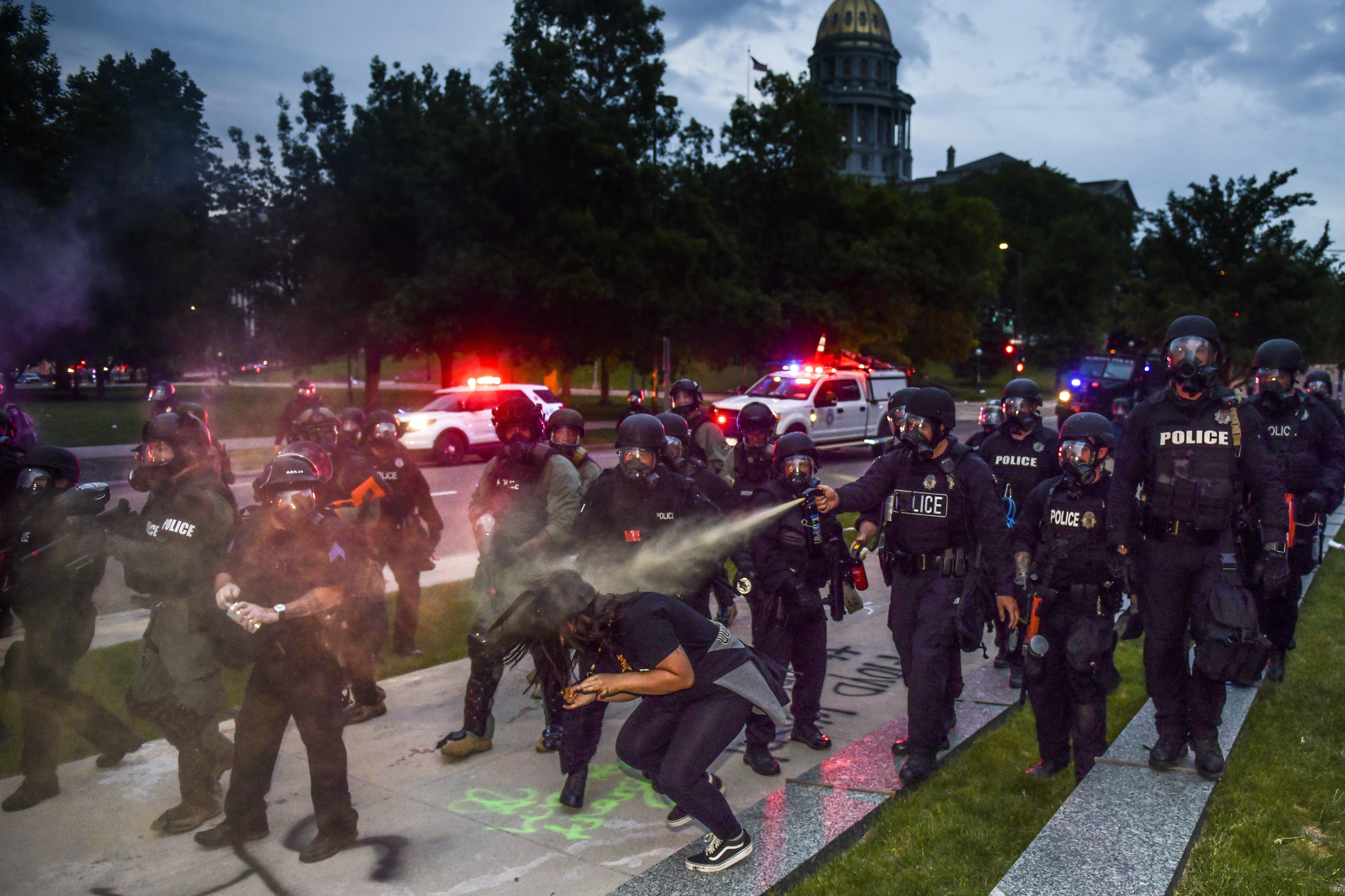 Police officers pepper spray a woman next to the Colorado State Capitol as protests against the death of George Floyd continue for a third night on May 30, 2020 in Denver, Colorado. 