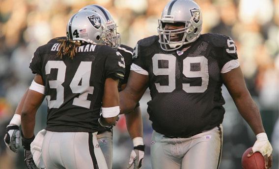 Defensive tackle Warren Sapp #99 of the Oakland Raiders celebrates with teammate cornerback Ray Buchanan #34 in the third quarter against the Tennessee Titans on December 19, 2004 in Oakland, California. 