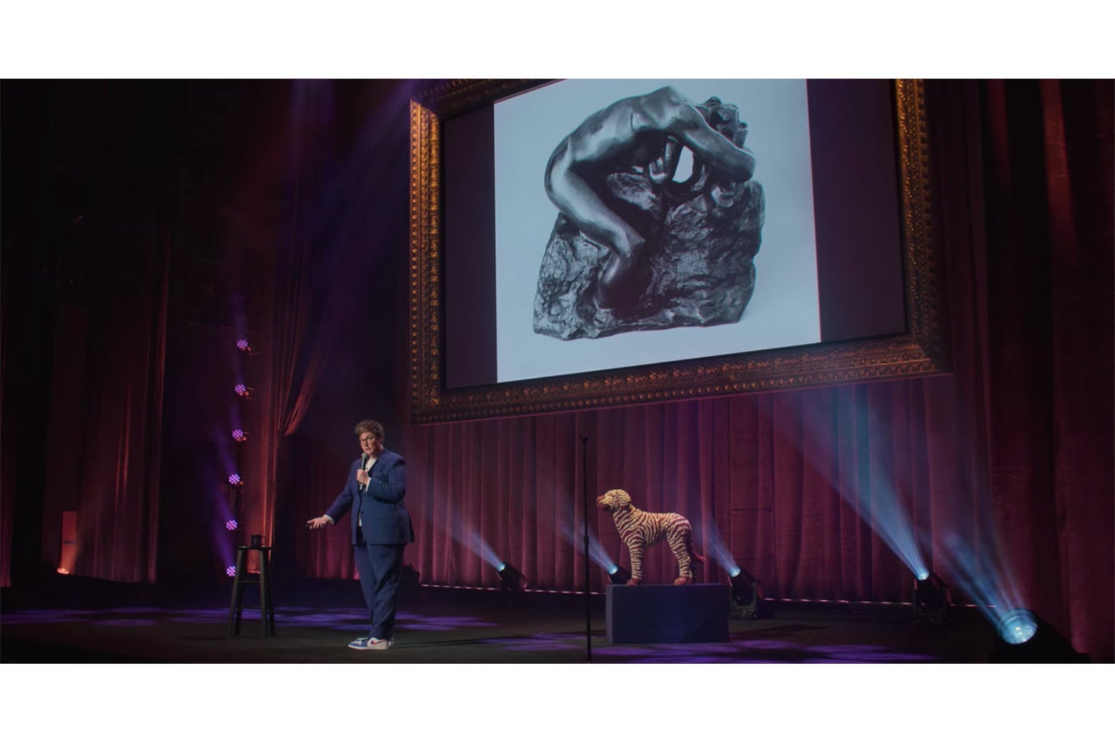 Hannah Gadsby stands in front of a photograph of a Rodin bronze of Andromeda.