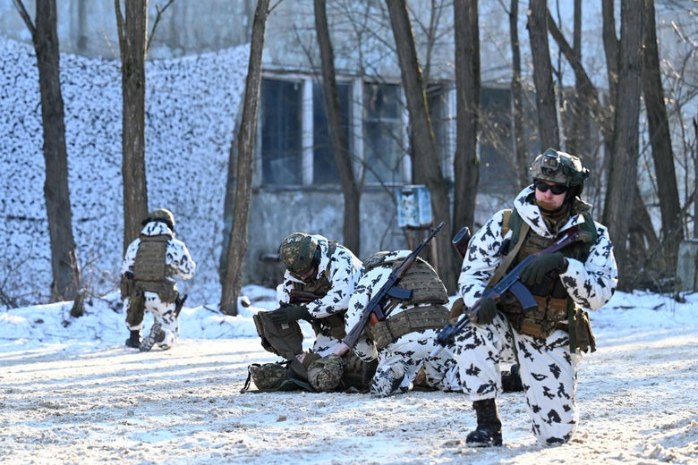 Troops in white camo wield guns and kneel on snow