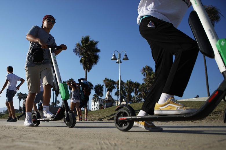 Two people ride Lime shared dockless electric scooters along Venice Beach on August 13, 2018 in Los Angeles, California. 
