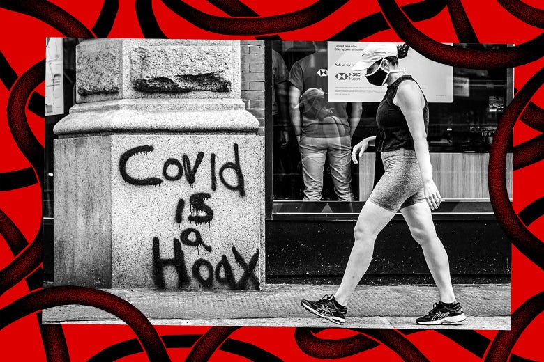 A person wearing a protective face mask next to graffiti that reads, "COVID is a hoax."