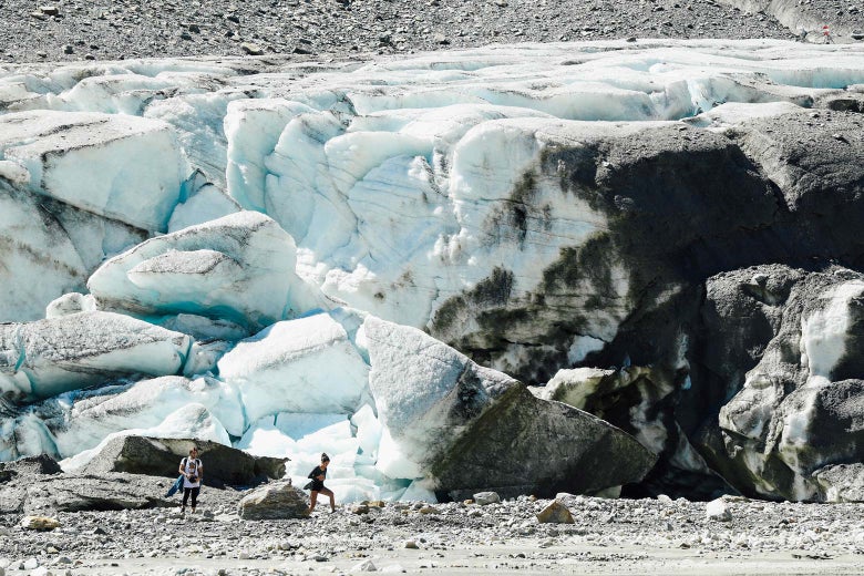 Visitors walk past collapsing, melting ice.