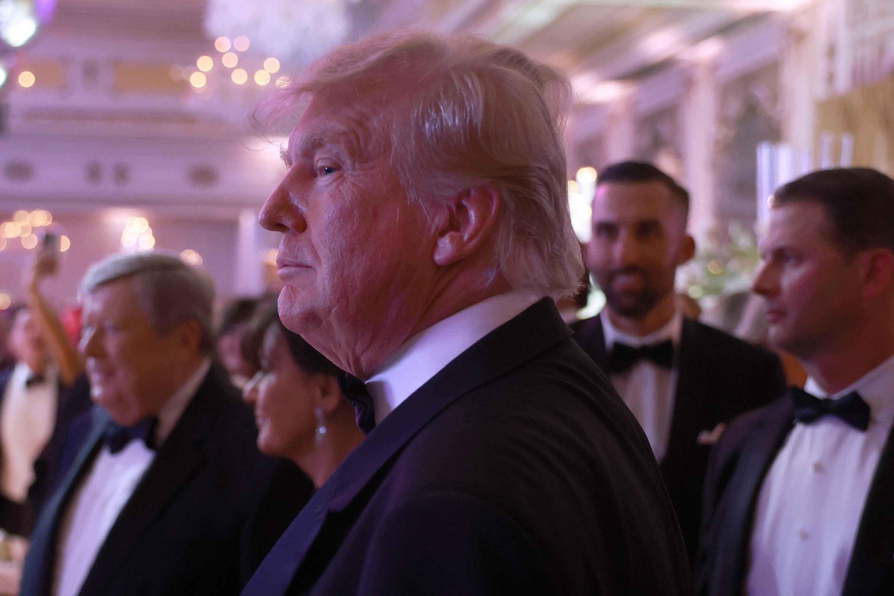 A side view of Trump's face. He's wearing a tuxedo and glowering.
