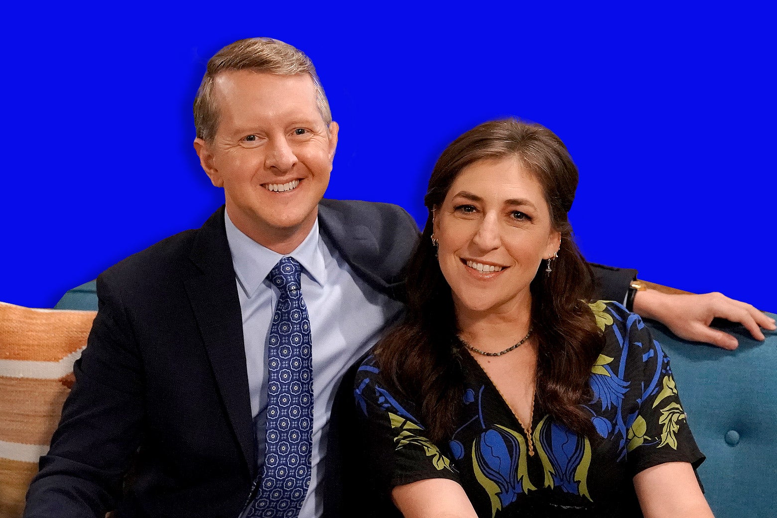 Ken Jennings and Mayim Bialik sitting together on a couch.