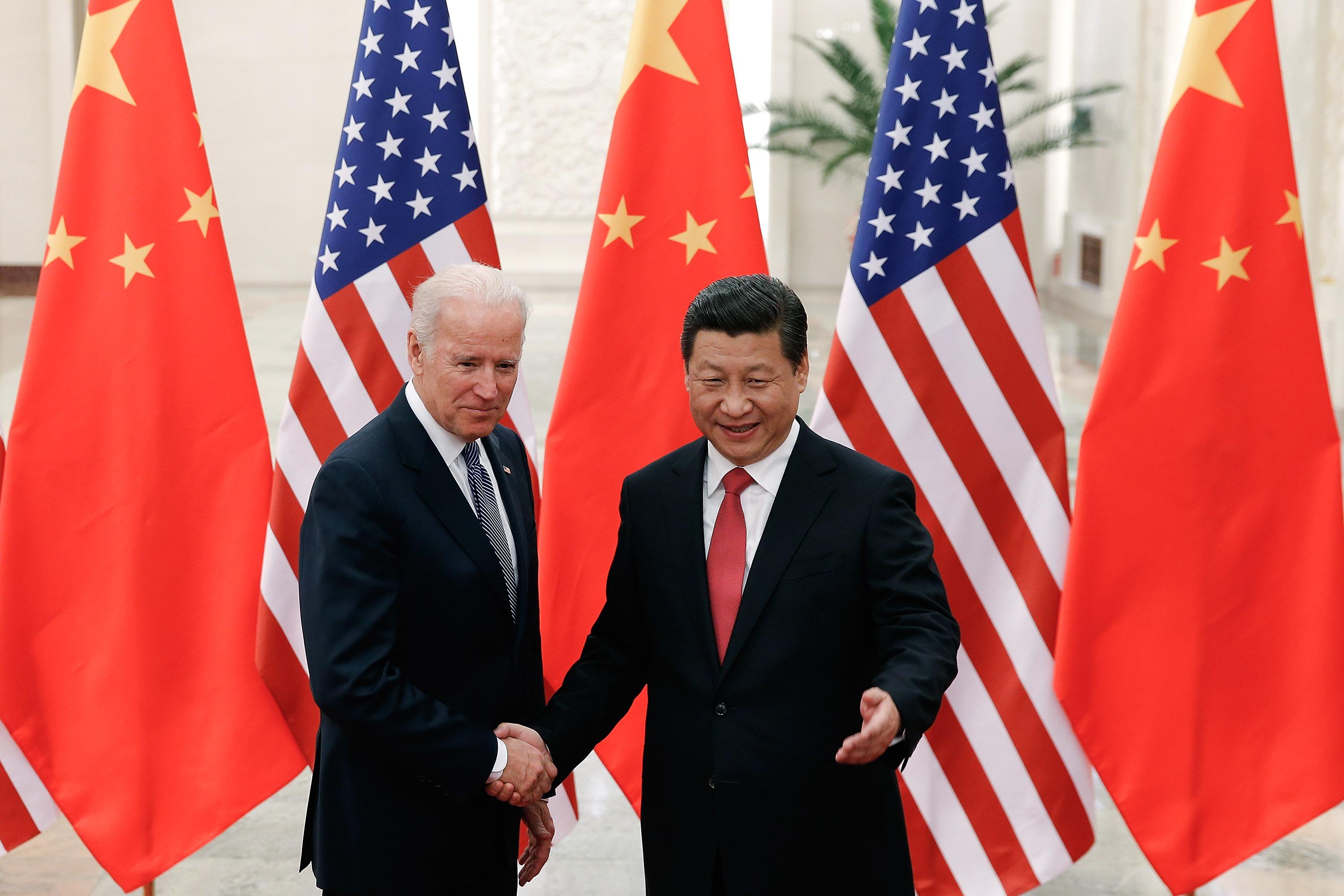 Biden and Xi shaking hands in front of U.S. and Chinese flags