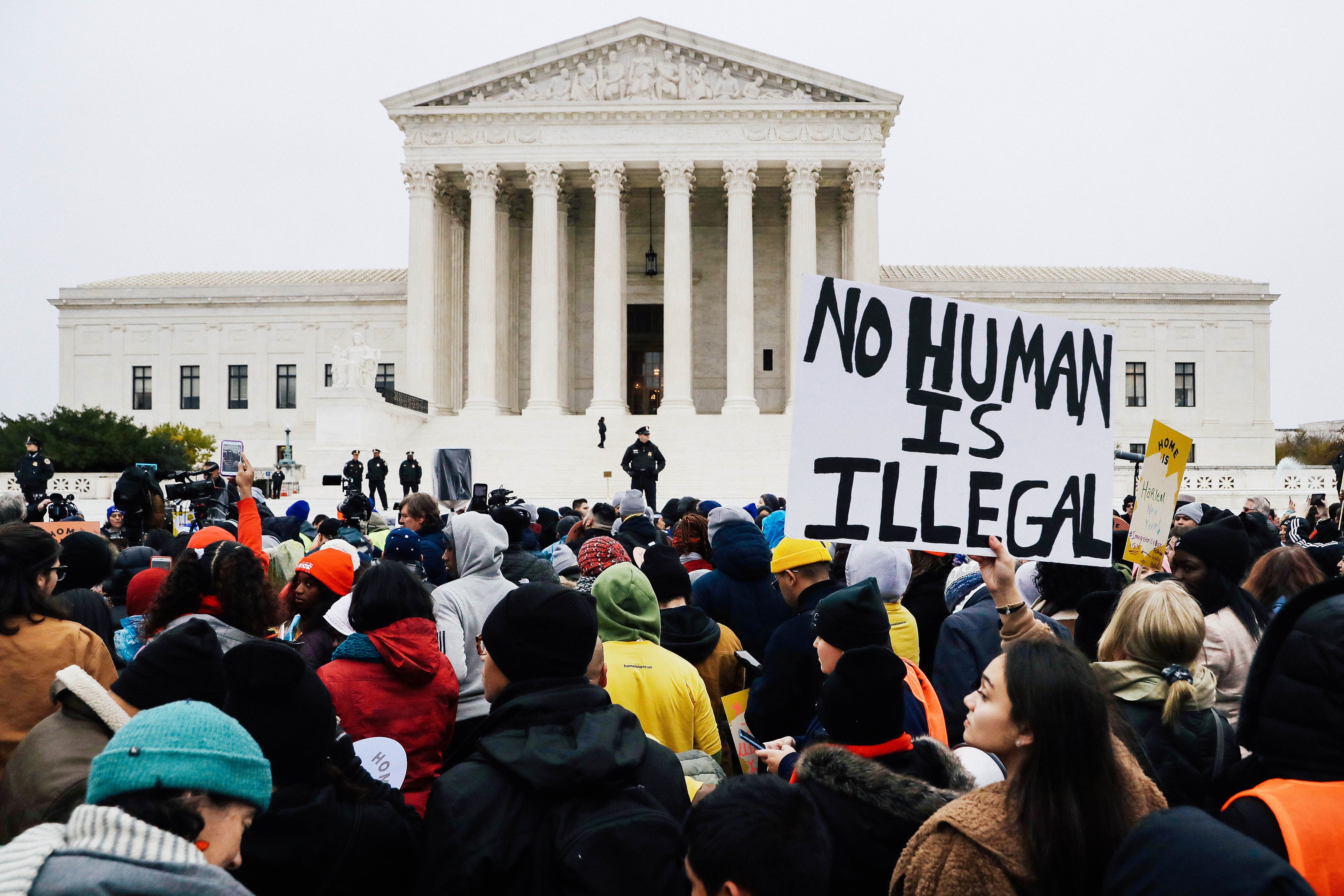 A crowd of demonstrators outside the Supreme Court. One poster reads "NO HUMAN IS ILLEGAL."
