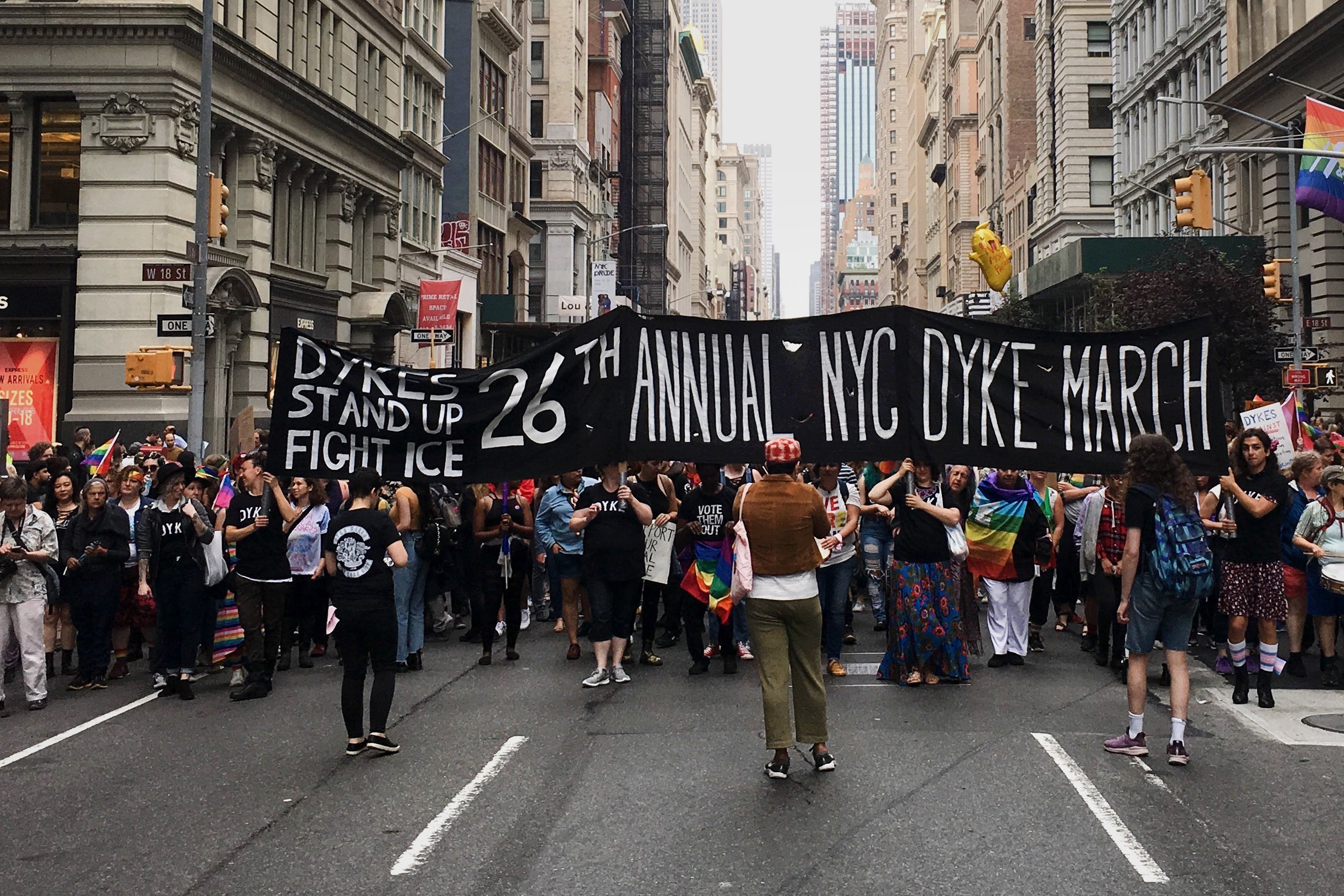 A view of the NYC Dyke March with a banner in the foreground.