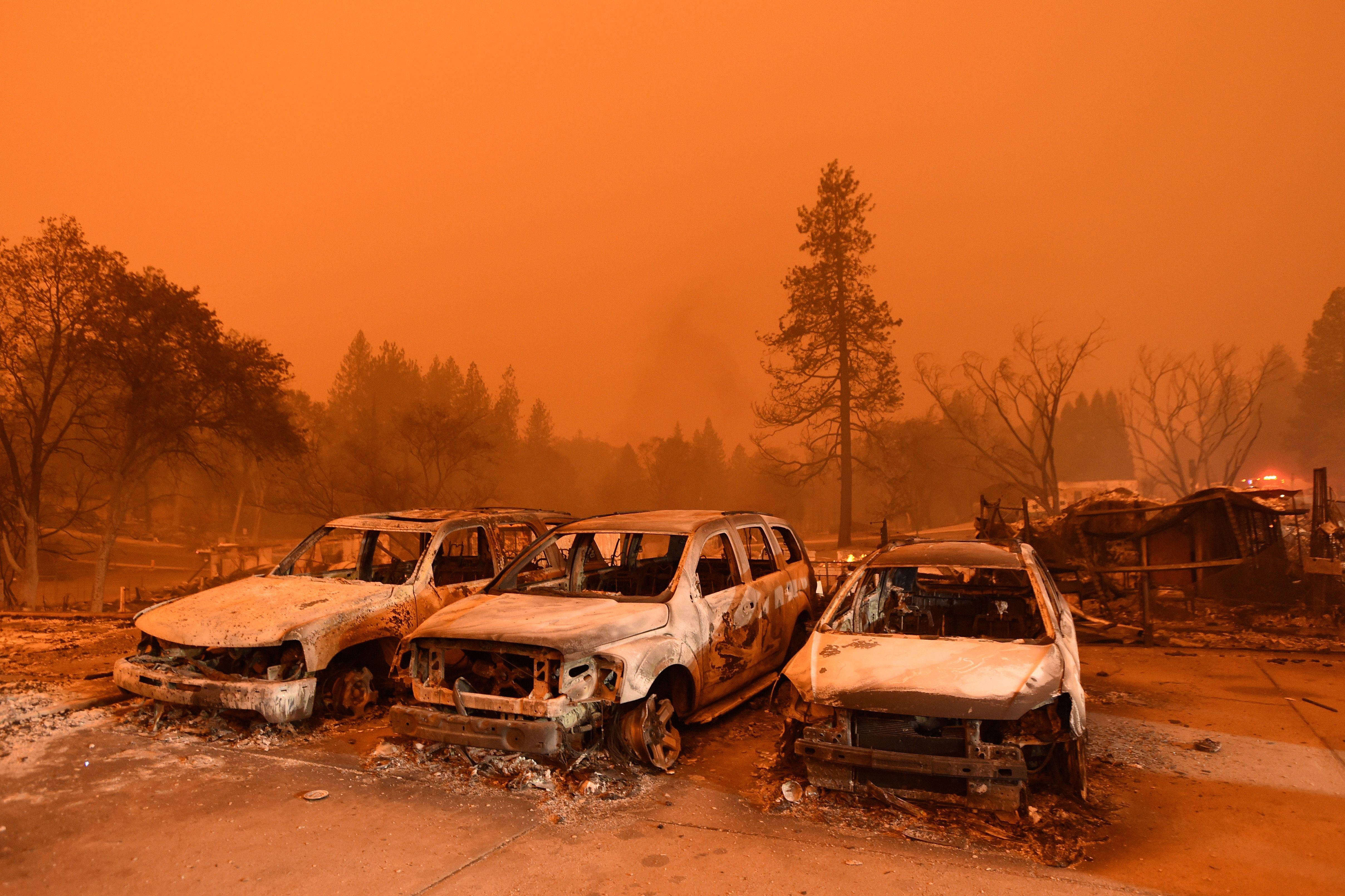 Burned vehicles in a parking lot engulfed in a smoky haze.