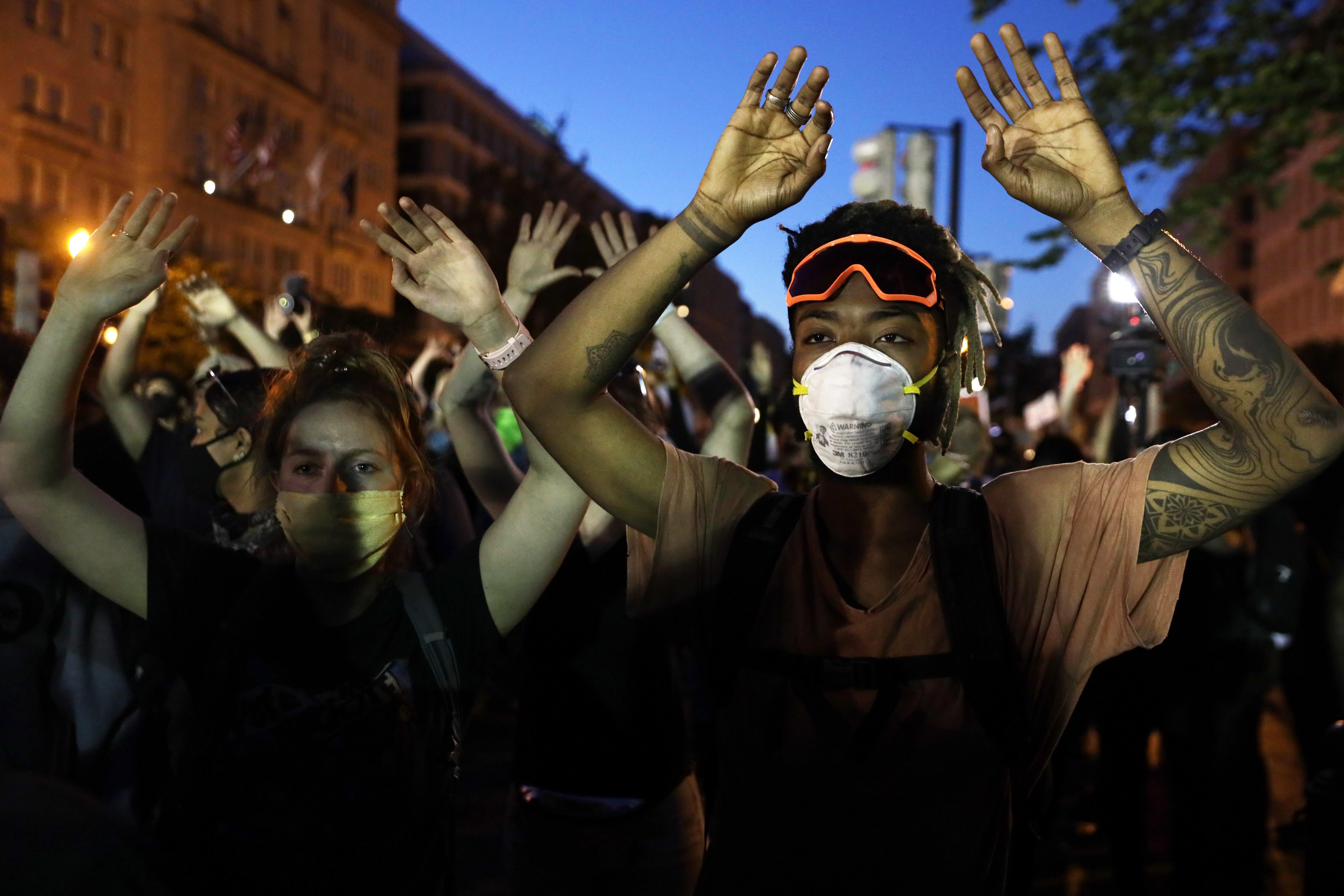 A line of protesters raise their arms in protest.