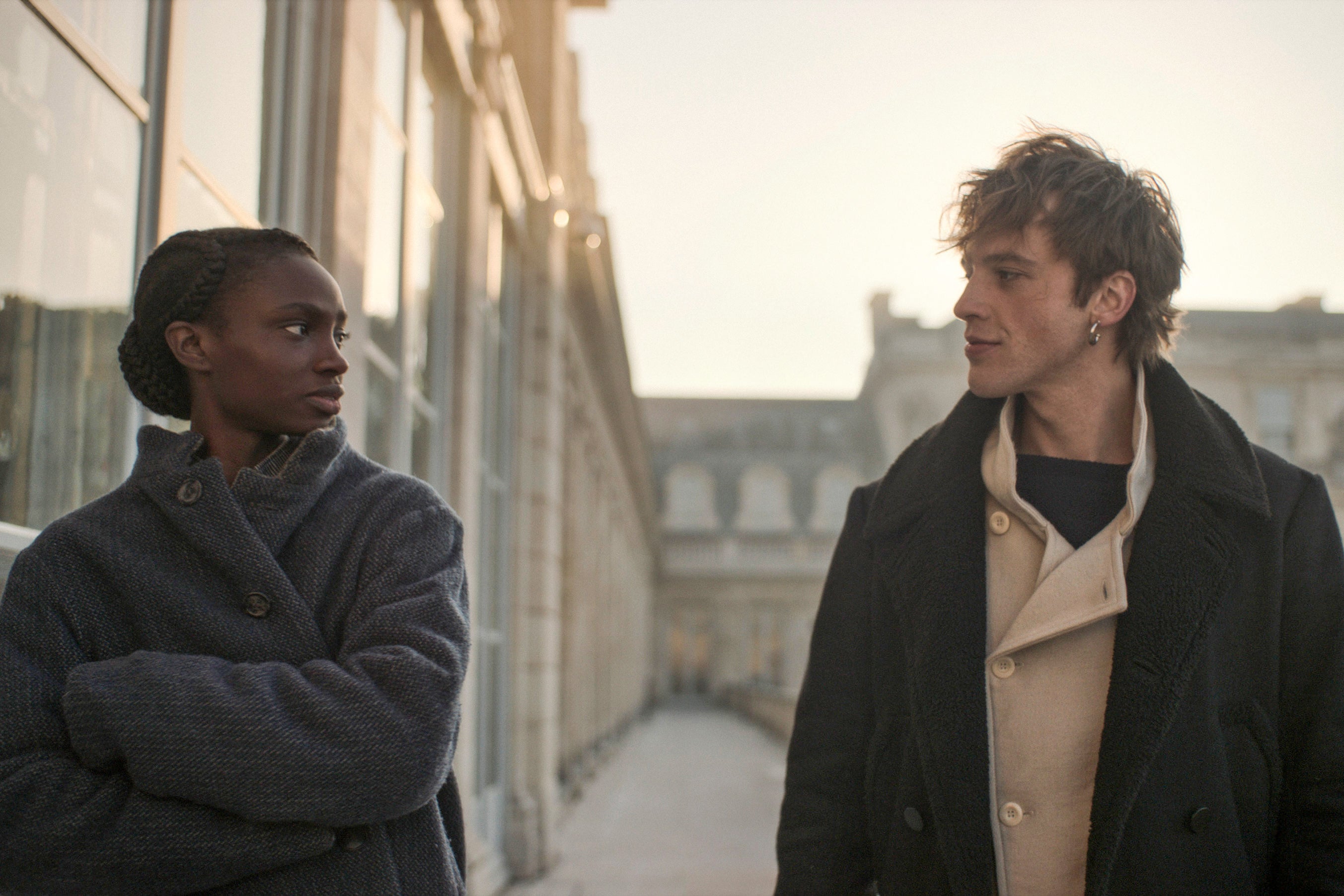 A Black woman and white man in nineteenth-century costume look at each other skeptically.