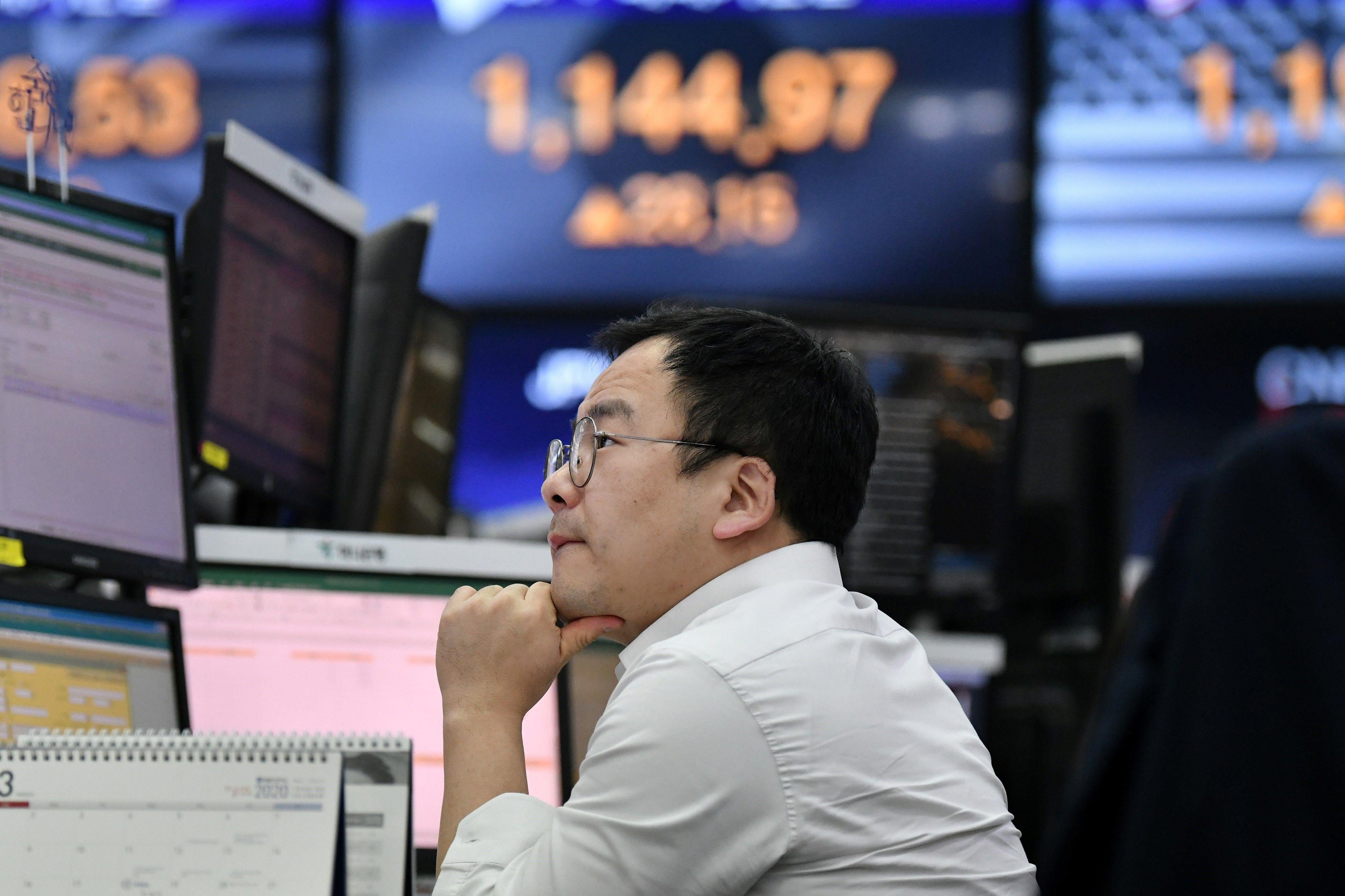A man sits in front of a computer with his chin resting in his hand