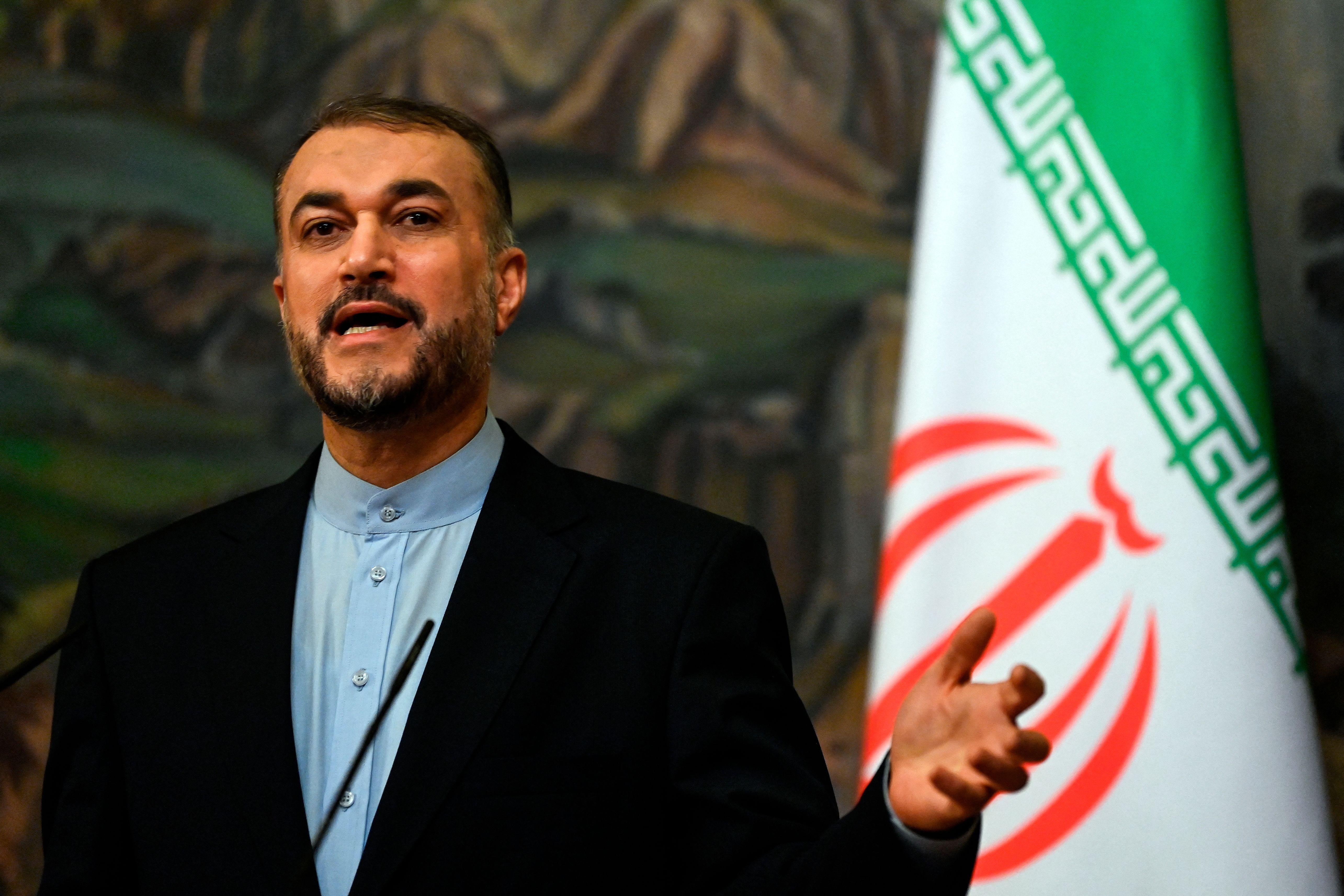 Hossein Amir-Abdollahian gestures as he speaks at a press conference with an Iranian flag behind him