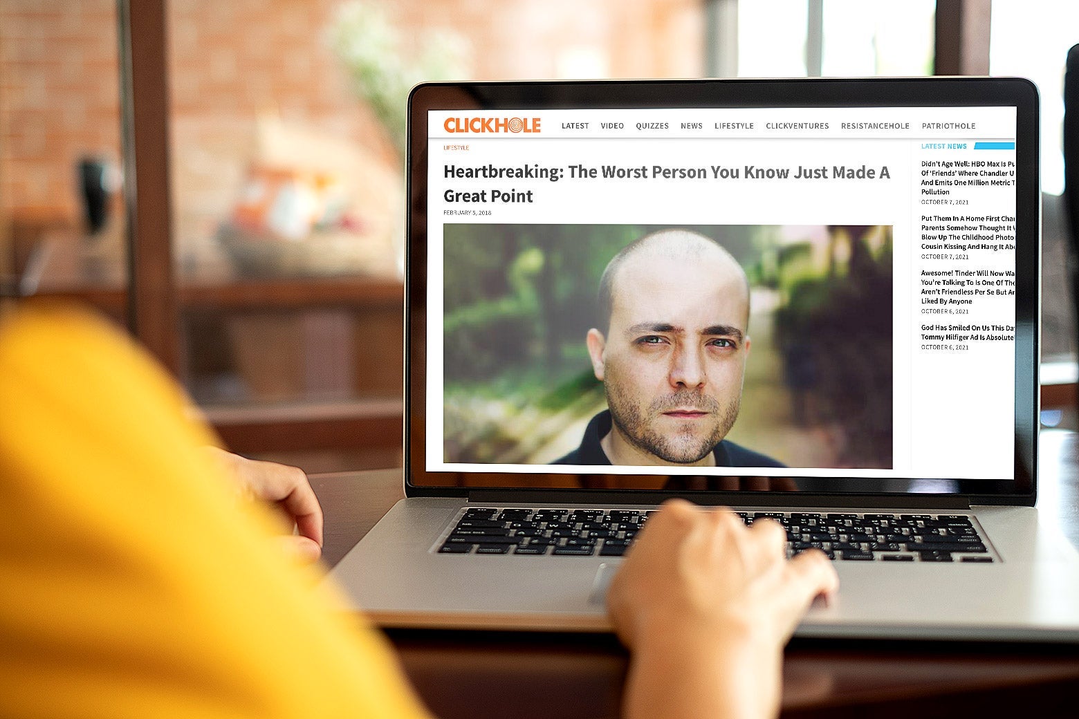 Person looking at laptop screen showing the top of the ClickHole post headlined "Heartbreaking: The Worst Person You Know Just Made a Great Point"