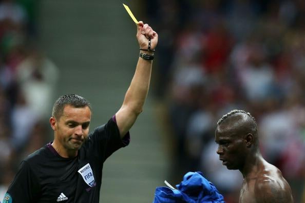 A ref gives Mario Balotelli a yellow card
