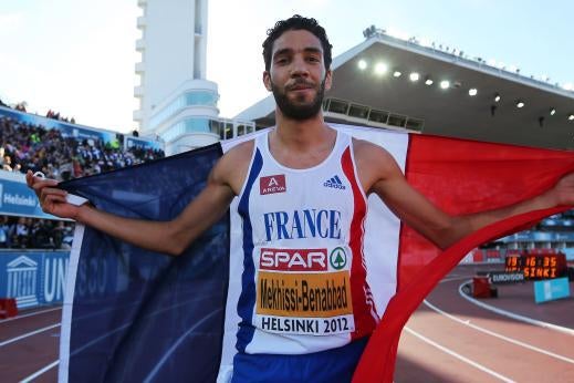Mahiedine Mekhissi-Benabbad holding a tricolor French flag behind him and smirking on the track