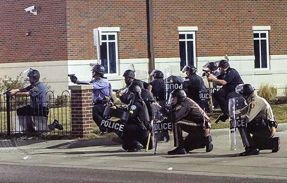 Police officers respond to a fellow officer hit by gunfire outside the Ferguson police headquarters in Ferguson, Missouri, on March 12, 2015
