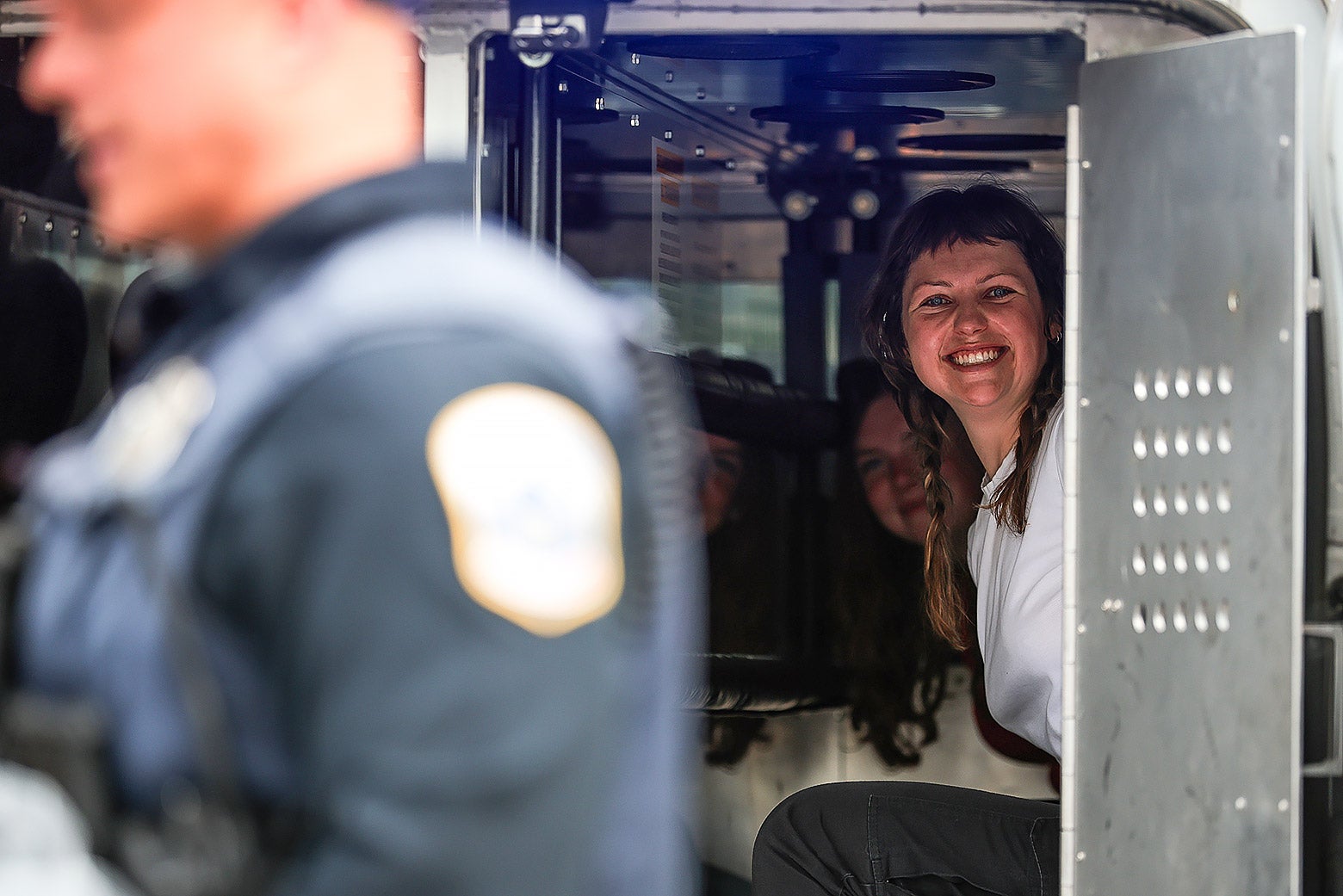White protesters smile from inside a police van at a recent anti-Trump demonstration.