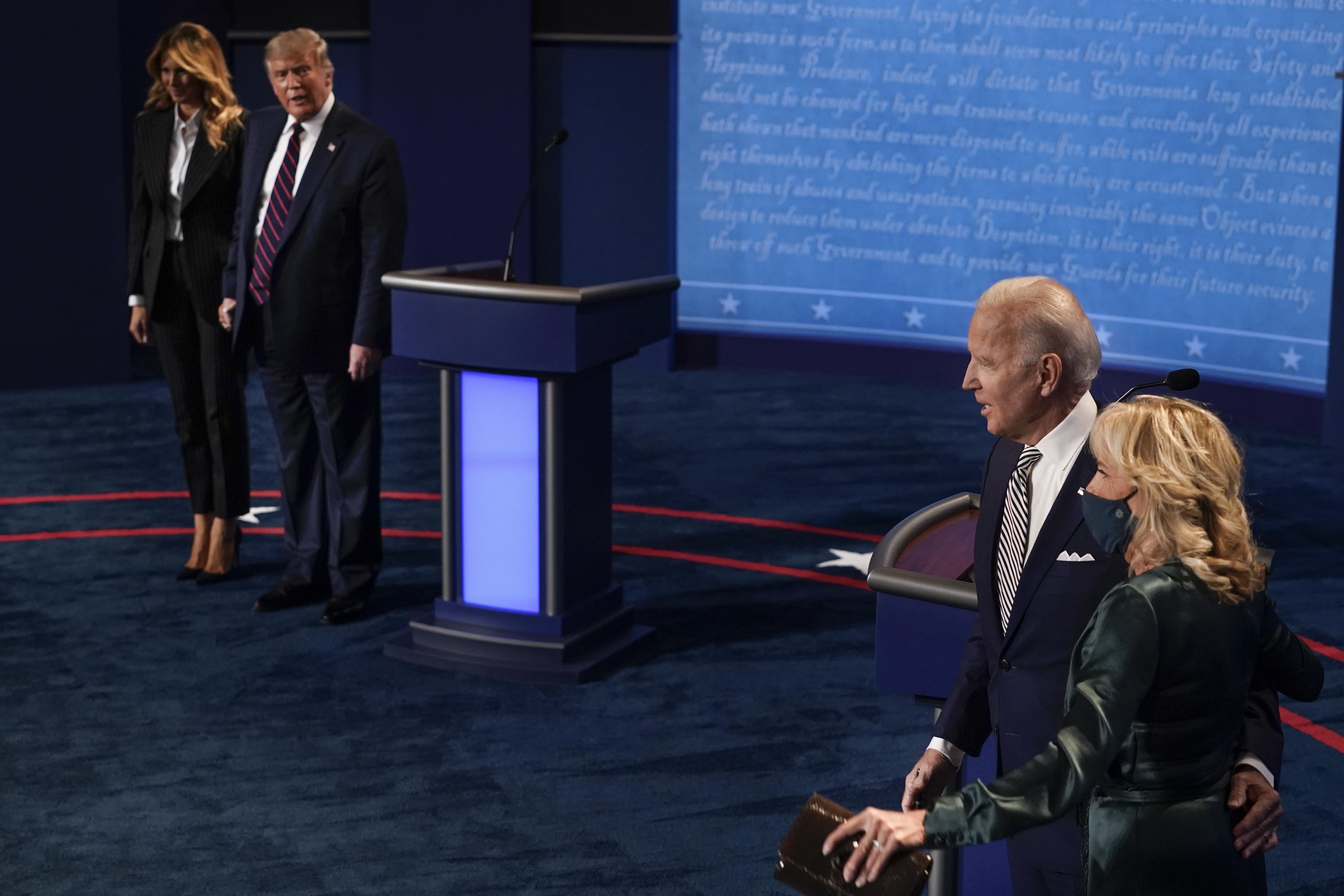 Donald Trump, standing beside Melania, stares at Jill and Joe Biden, standing beside Biden's podium. Jill Biden is the only one wearing a mask.