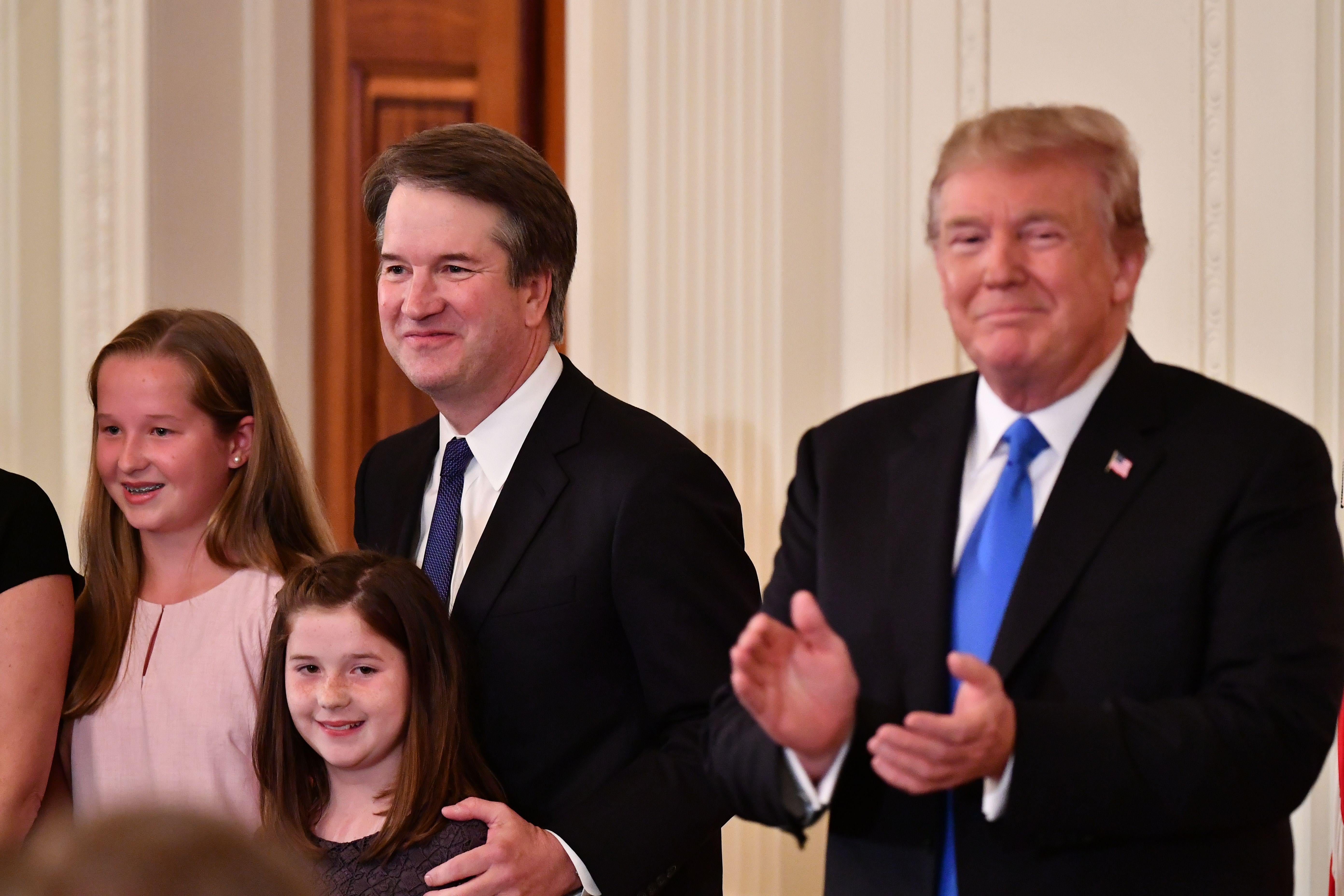 Supreme Court nominee Brett Kavanaugh, his wife Ashley Estes Kavanaugh (off frame) and their two daughters stand by President Donald Trump after he announced his nomination in the East Room of the White House on July 9, 2018.