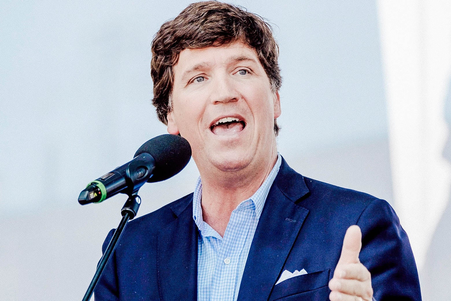 Tucker Carlson onstage speaking at a mic