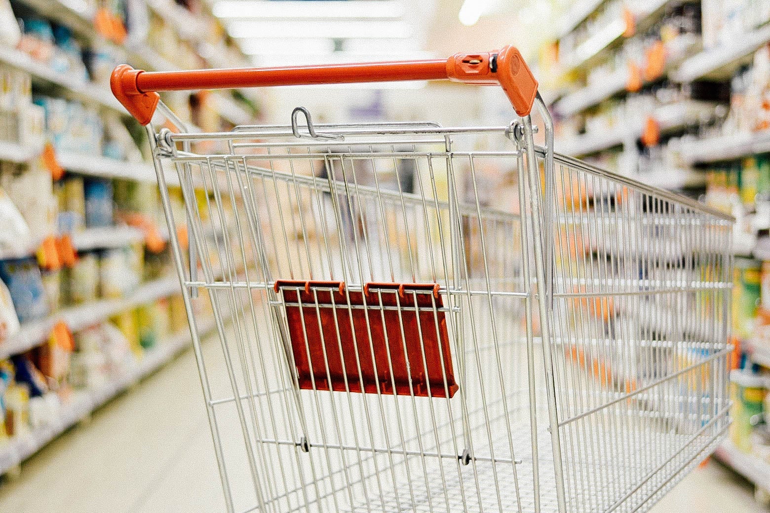 An empty shopping cart is seen in a supermarket aisle.
