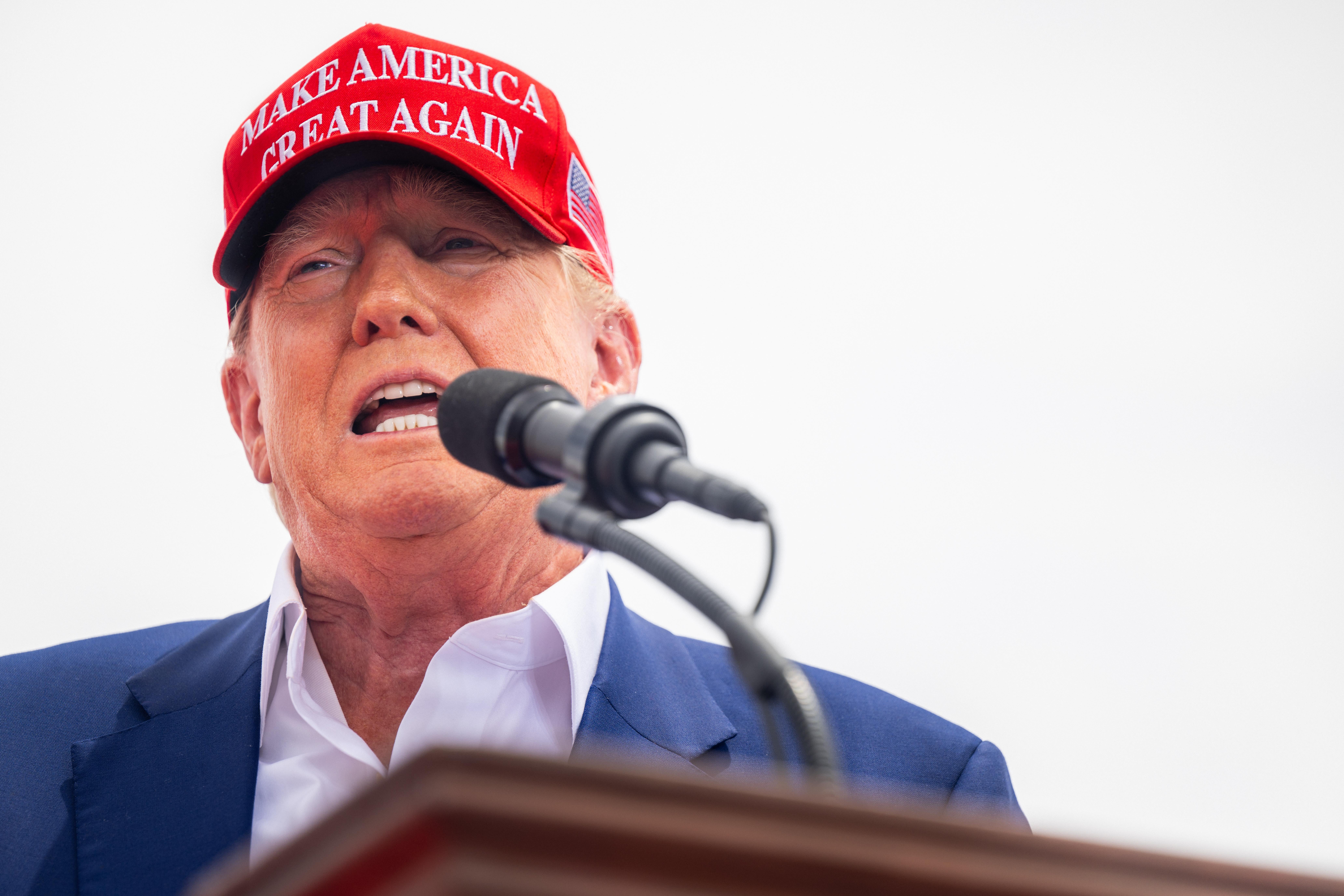Former U.S. President Donald Trump wears a MAGA hat and speaks during a campaign rally.