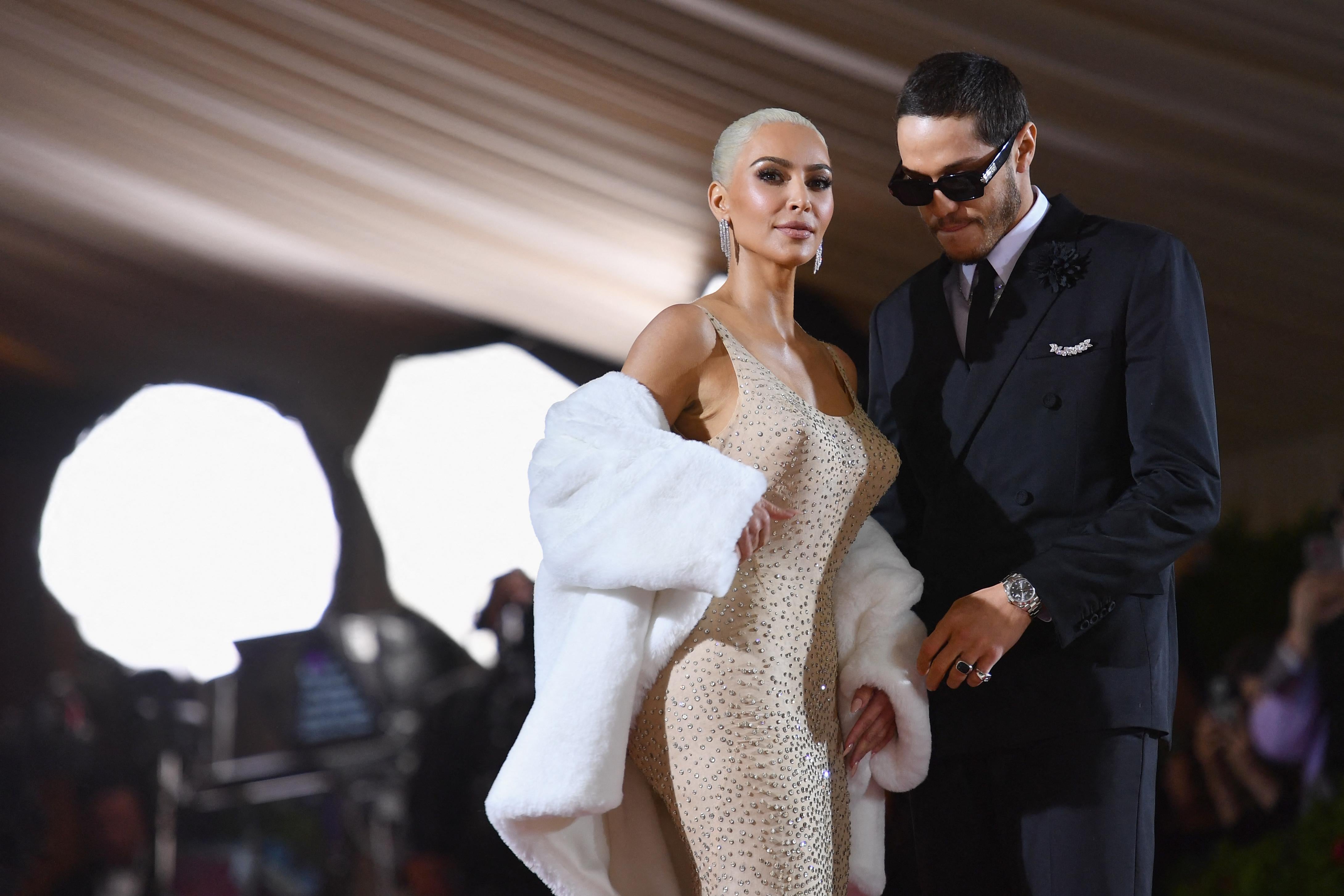 Kim Kardashian and Pete Davidson at the Met Gala at the Metropolitan Museum of Art on May 2, 2022, in New York. She wears a beige gown with a fur stole and he wears a suit and sunglasses.