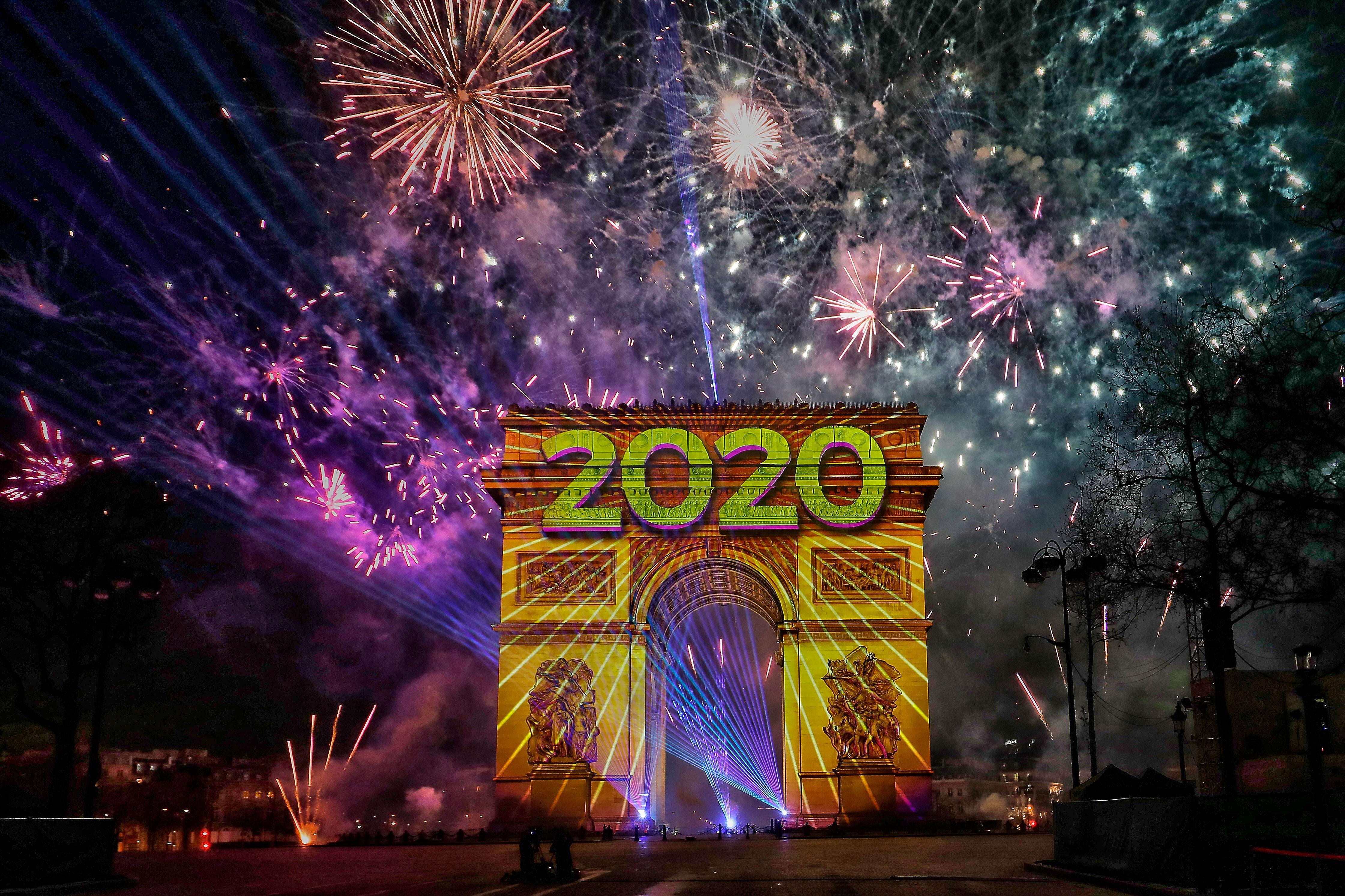Fireworks go off and "2020" is projected onto the Arc de Triomphe in Paris during the New Year's celebration.