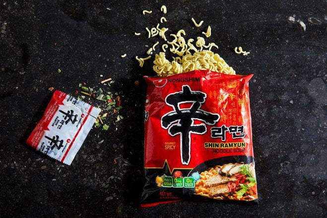 Hard noodles spill out of a packet of Shin Ramyun.