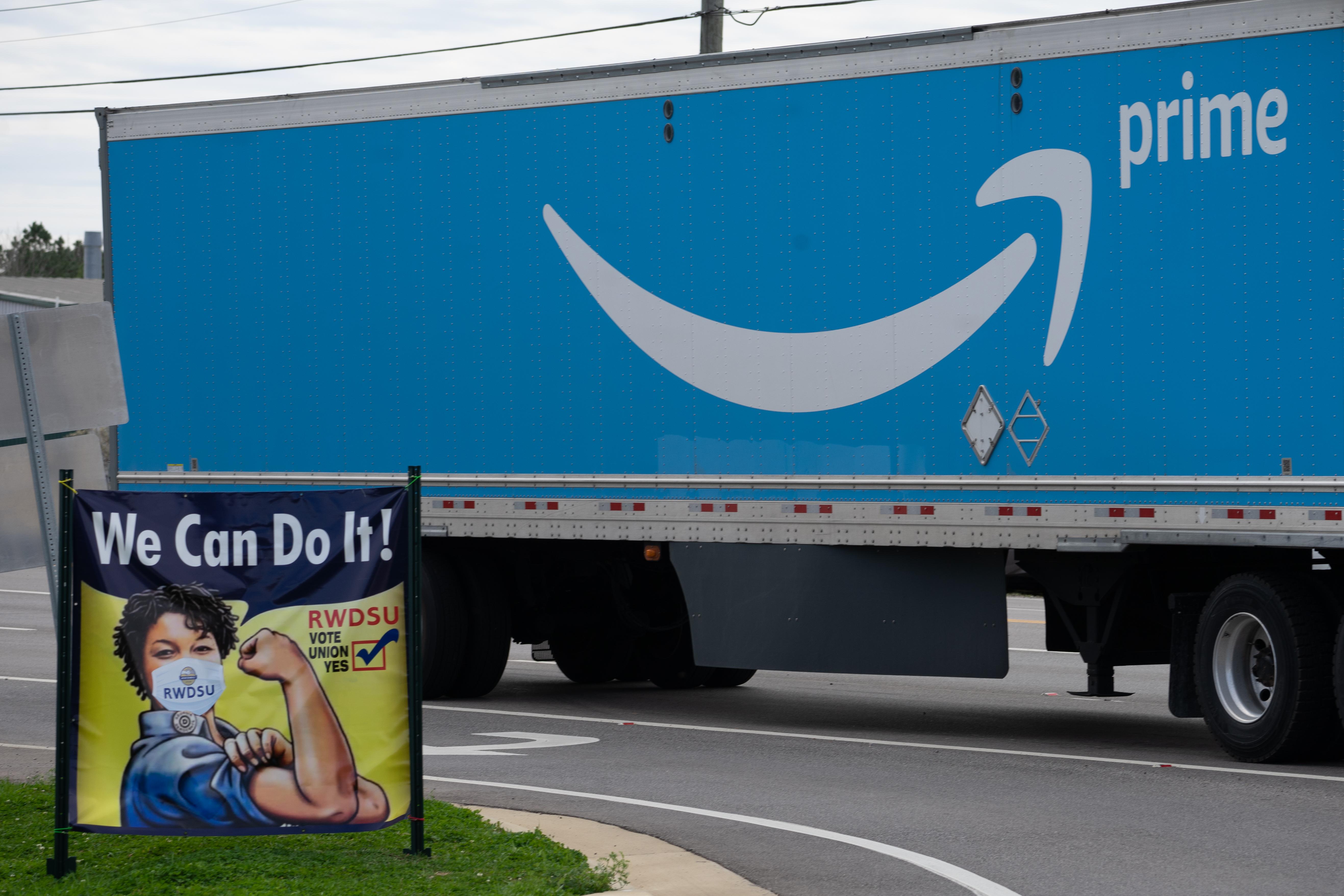 An Amazon Prime truck drives past a Rosie the Riveter–style pro-union sign outside an Amazon fulfillment center in Birmingham.