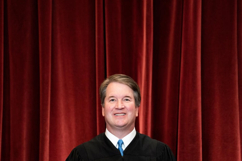 Kavanaugh smiling in his robes in front of a red curtain