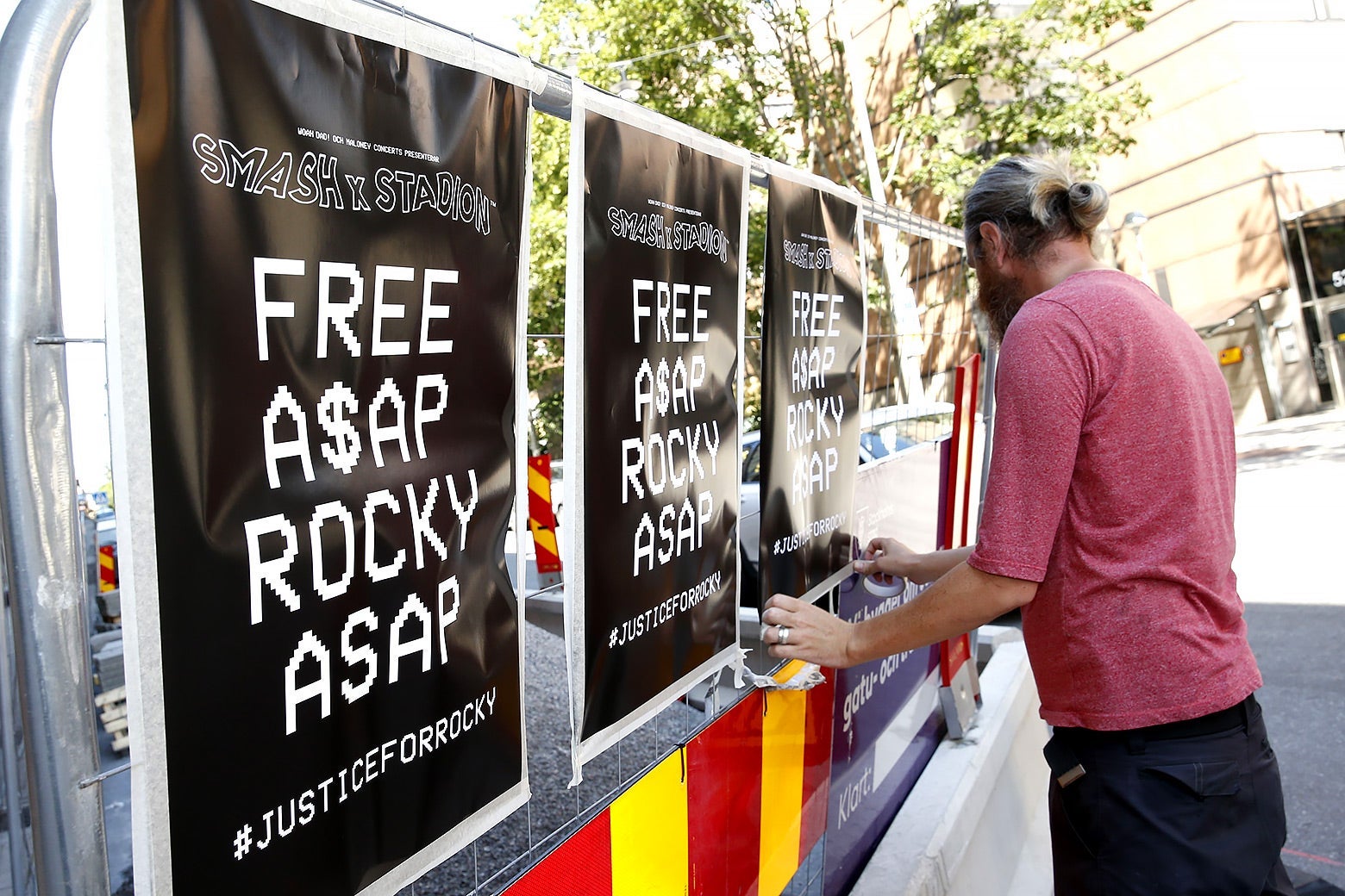 A man displays posters advocating for ASAP Rocky's release.